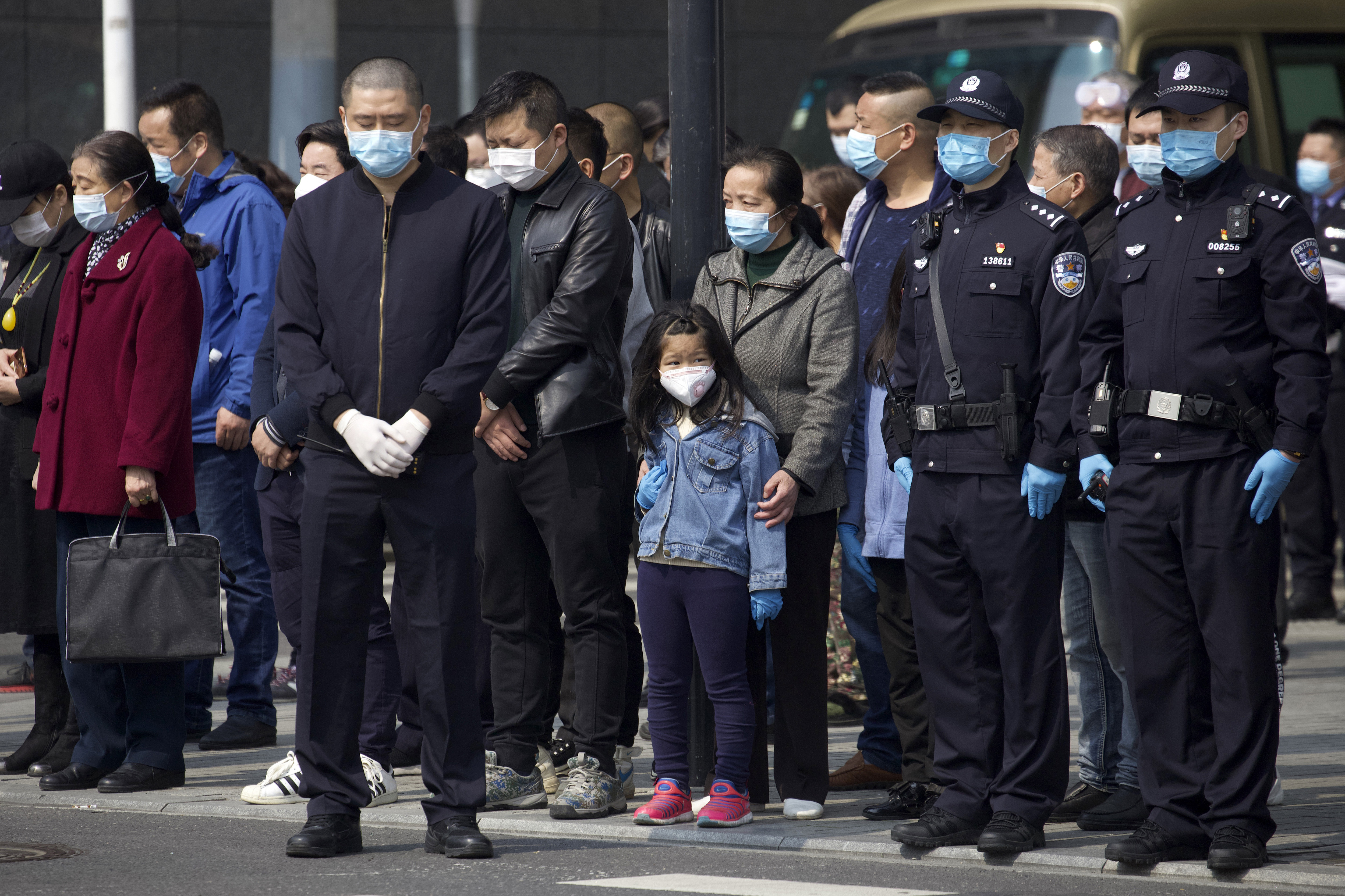 People bow their heads during a national moment of mourning for victims of coronavirus in Wuhan in central China's Hubei Province