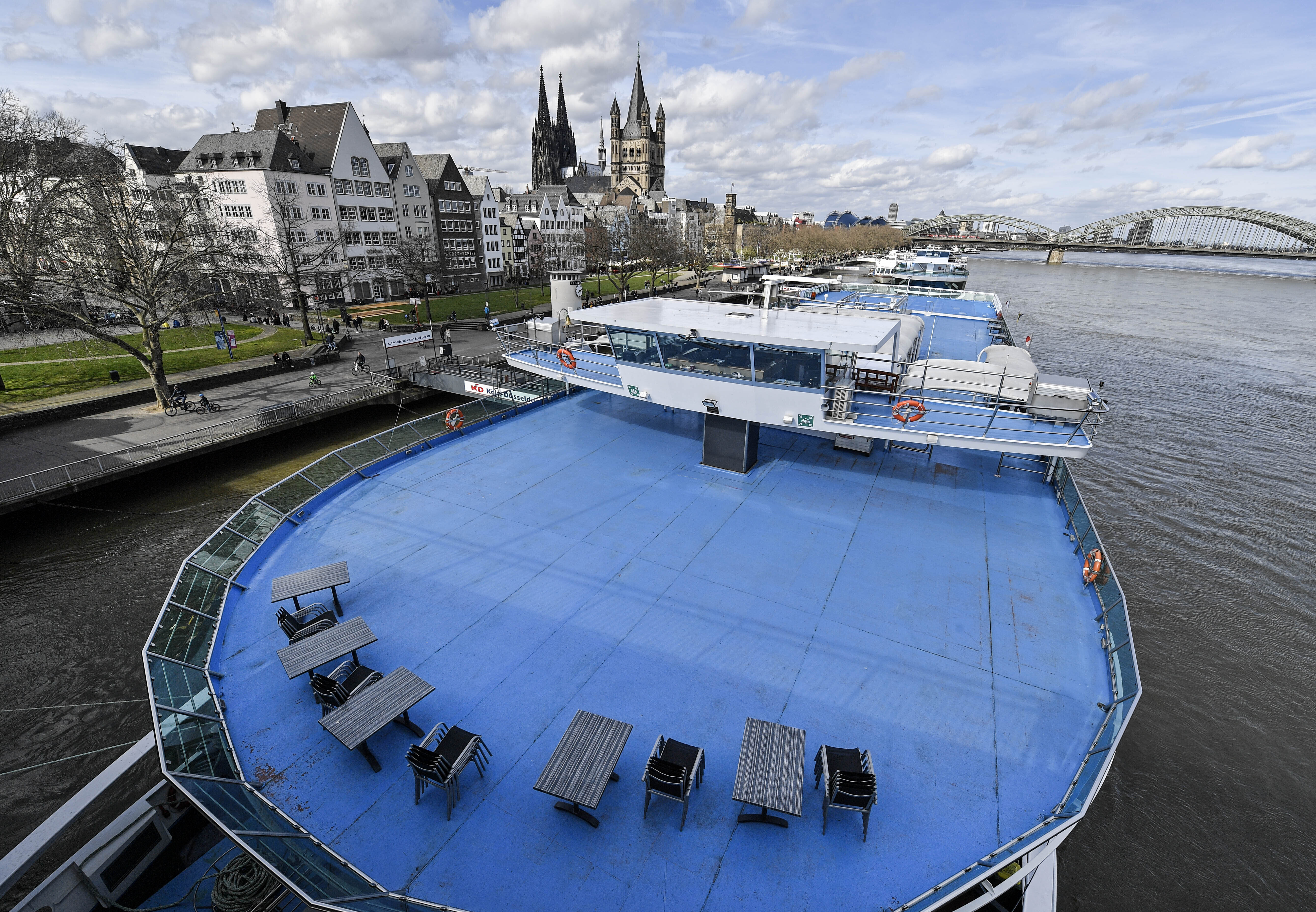 In this Sunday, March 15, 2020 file photo, chairs and tables are stored on the empty deck of a river cruise ship in Cologne, Germany.