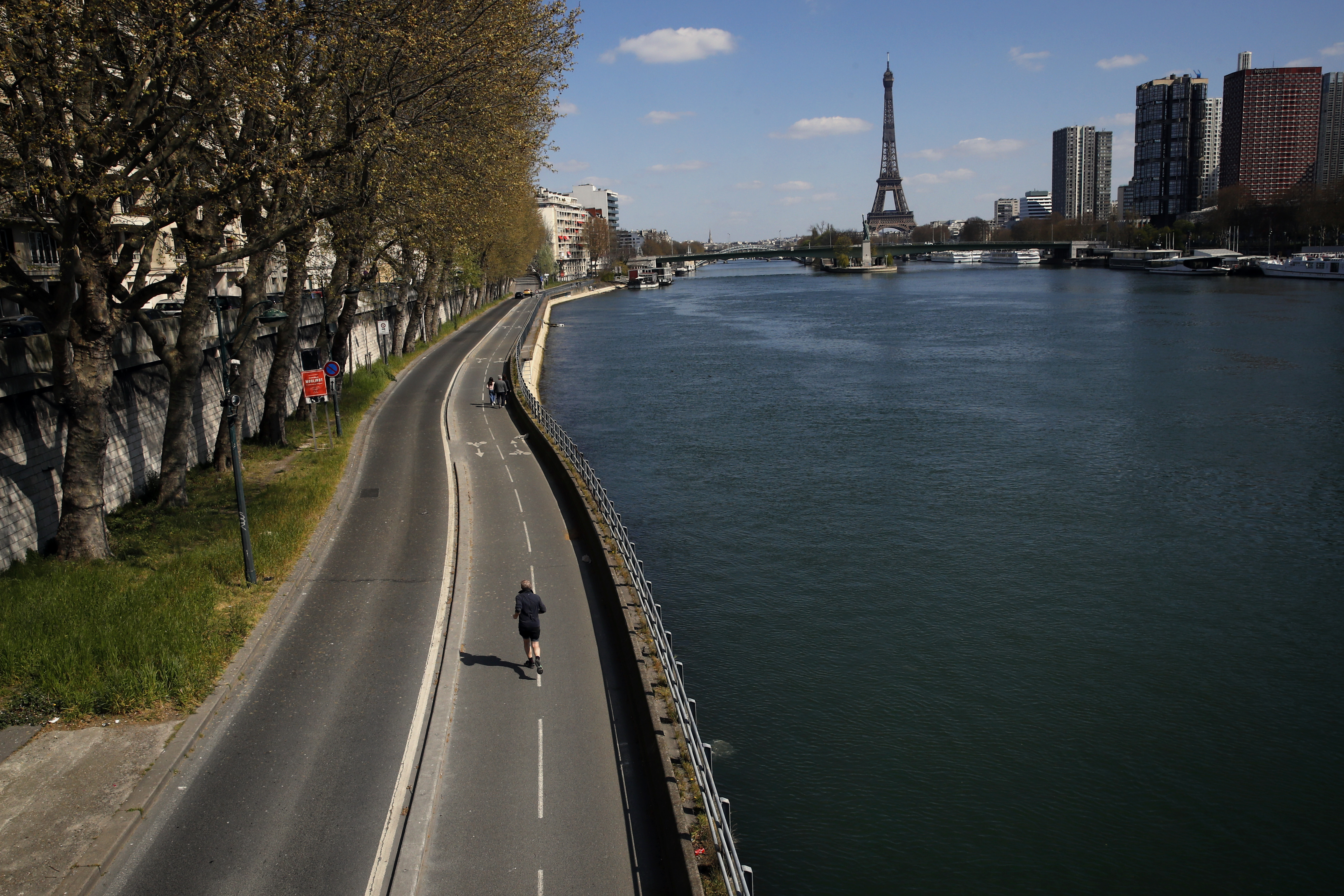 In this Saturday, April 4, 2020 file photo, a man jogs on an empty street along the Seine river in Paris.