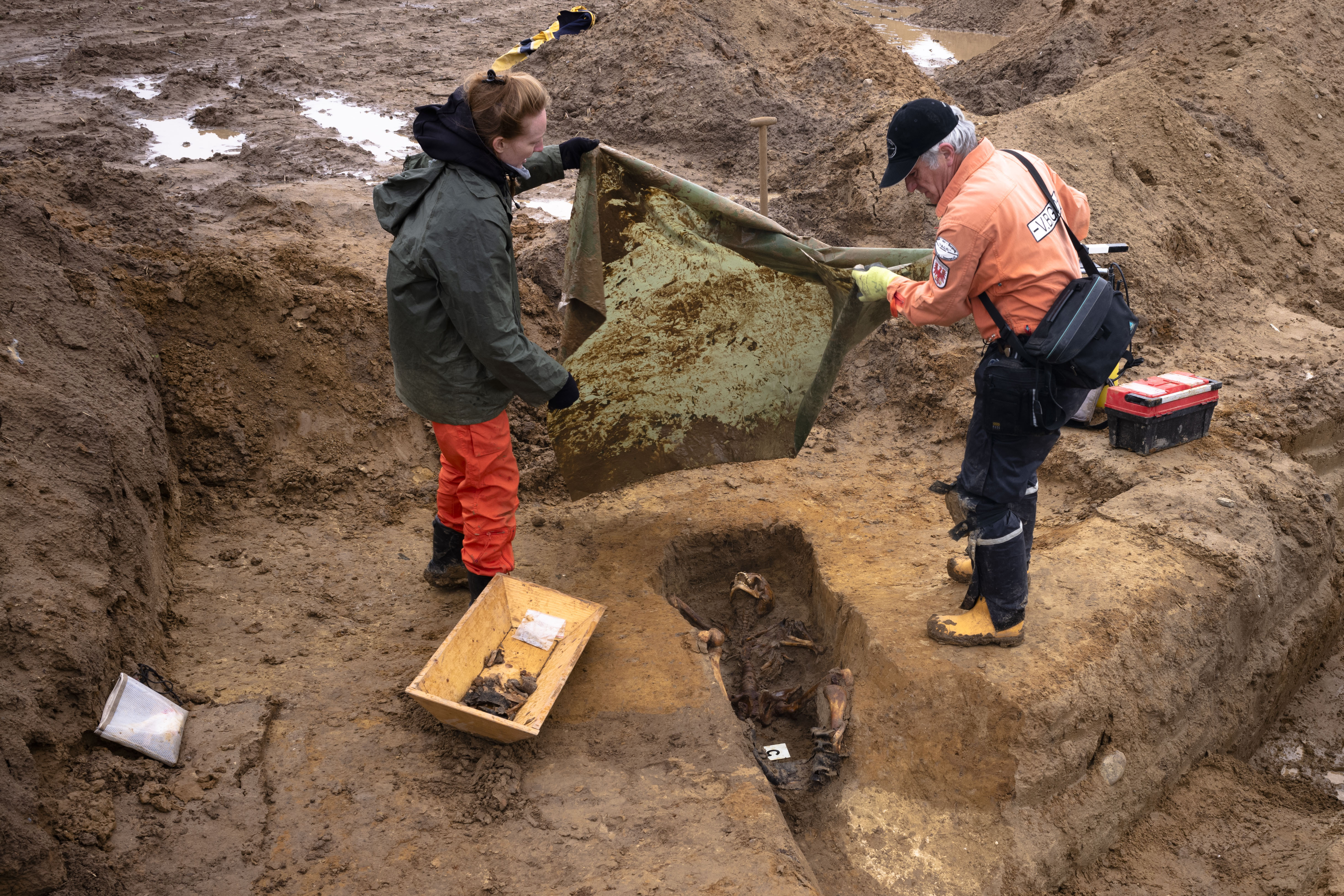 Laura Tradii, left, Social Anthropologist at the University of Cambridge and Werner Schulz, right, an excavation technician, cover the remains of a Soviet soldier during a search for fallen WWII soldiers near the village of Klessin in Germany