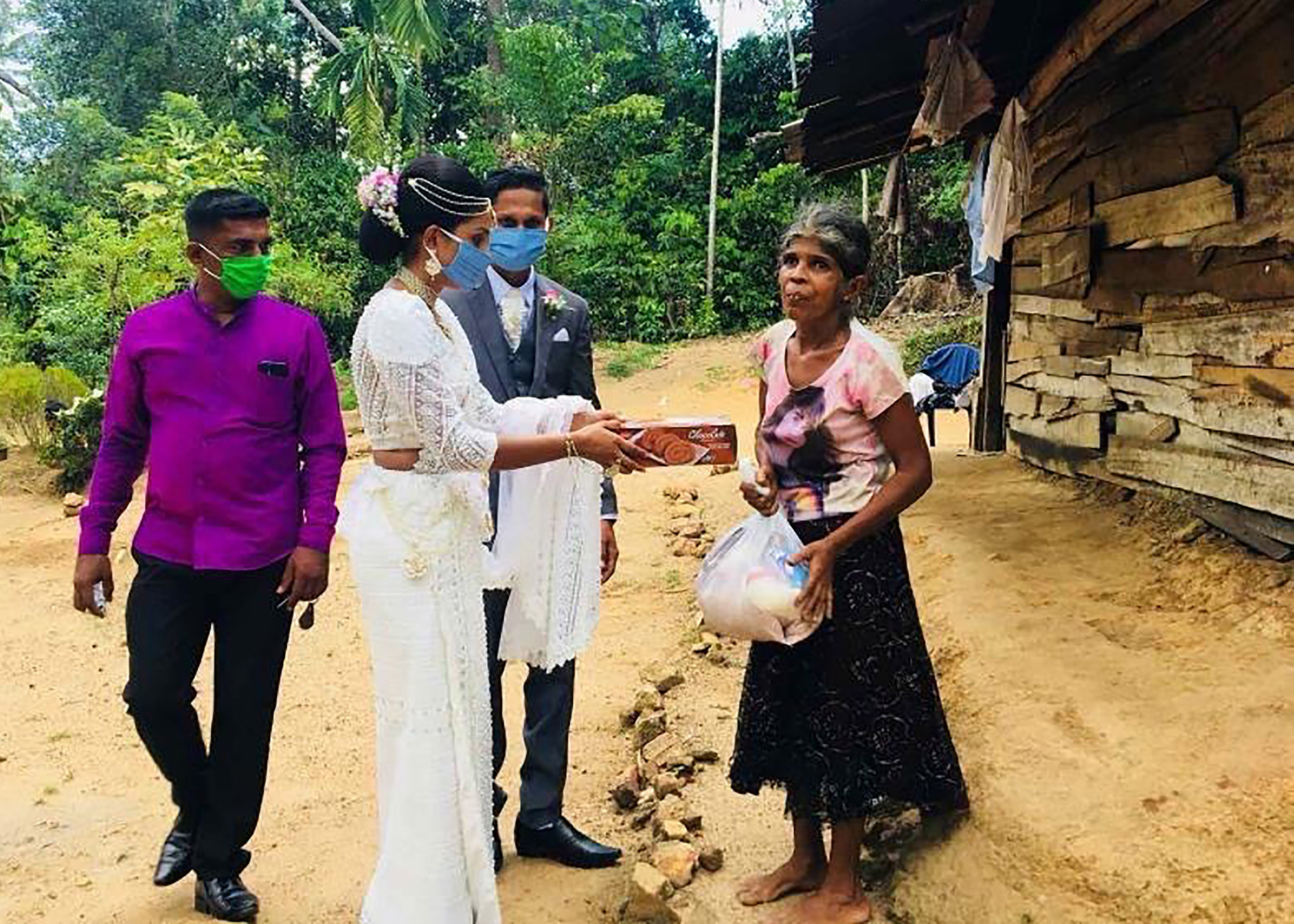 Pawani Rasanga hands a gift packet to an elderly woman, watched by her husband Darshana Kumara Wijenarayana in the small town of Malimbada, about 160 kilometers, South of the capital Colombo.