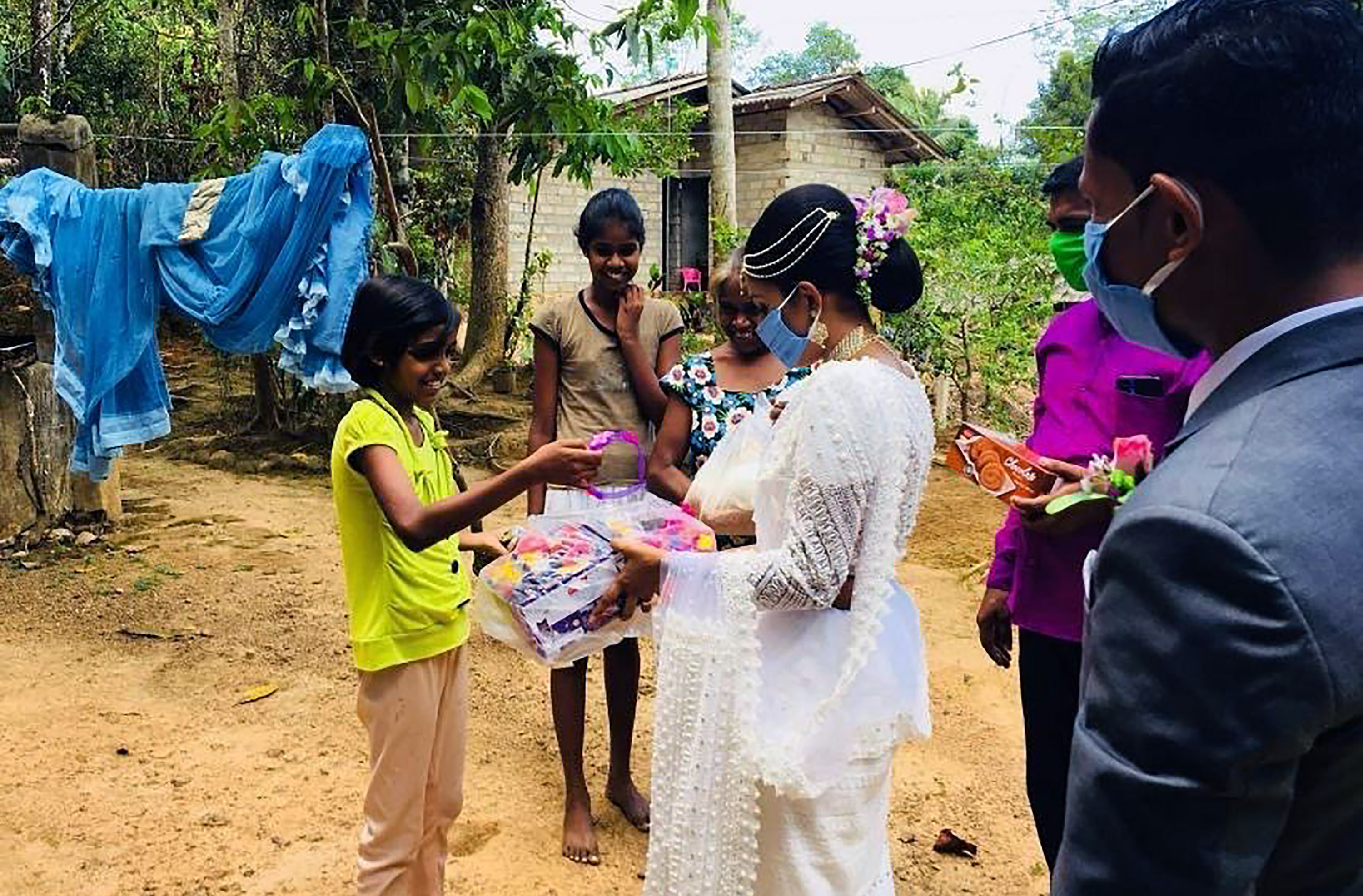 Pawani Rasanga hands a packet to a young girl, watched by her husband Darshana Kumara Wijenarayana in the small town of Malimbada, about 160 kilometers, south of the capital Colombo.