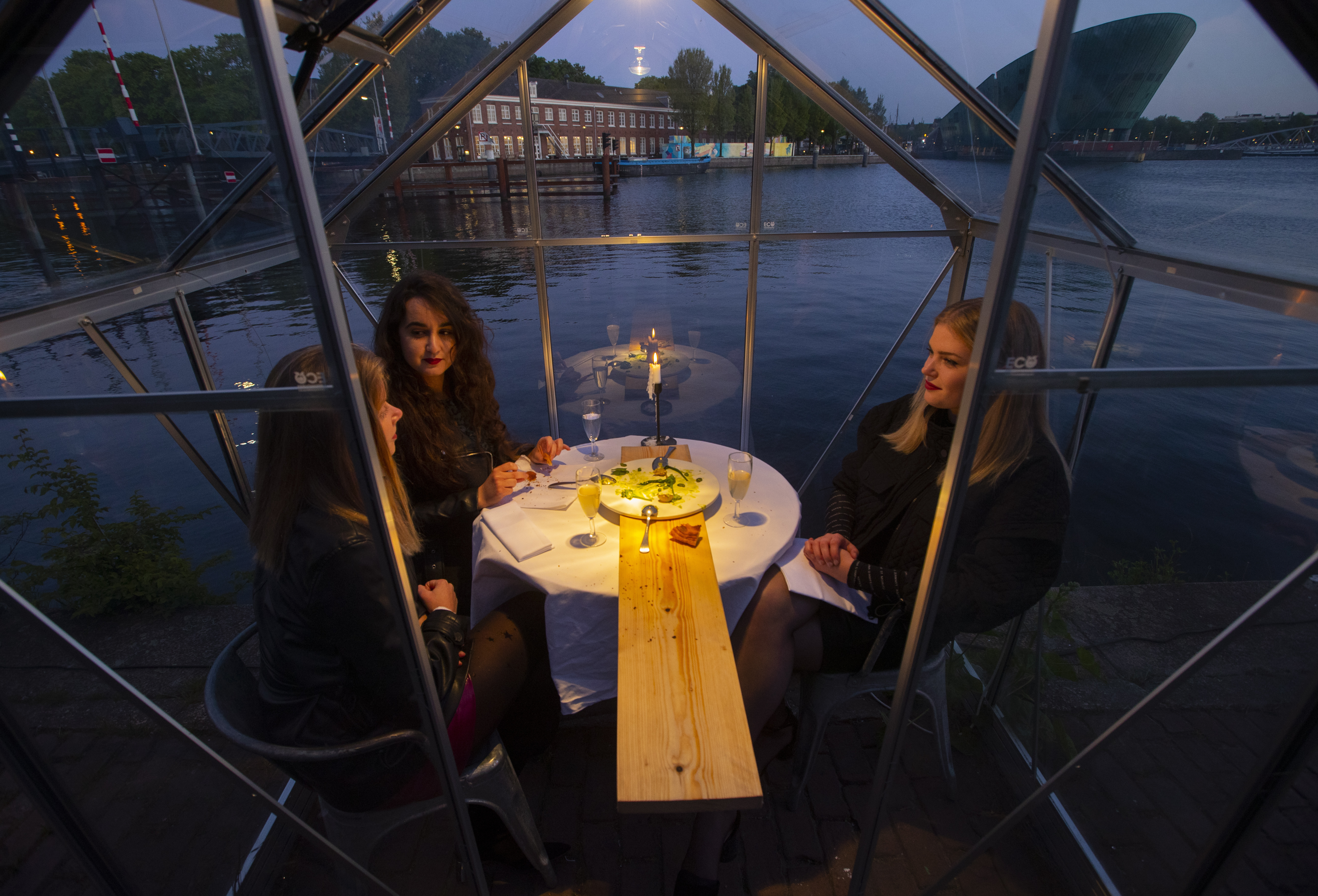 Mediamatic restaurant serve food to volunteers seated in small glasshouses.