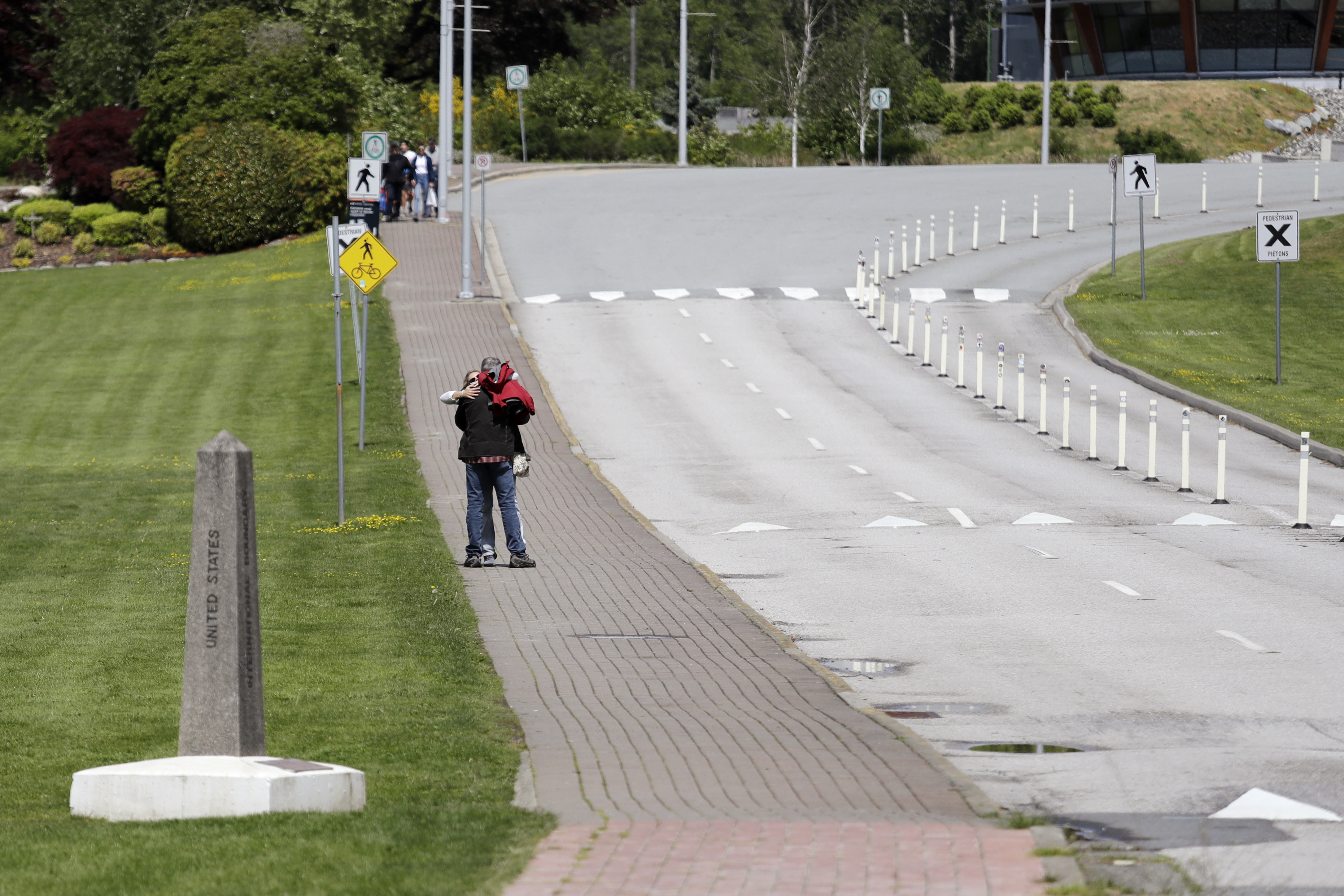 Two people embrace after meeting at the border between the U.S. and Canada at Peace Arch Park, where traffic is almost nonexistent, in Blaine, Washington.