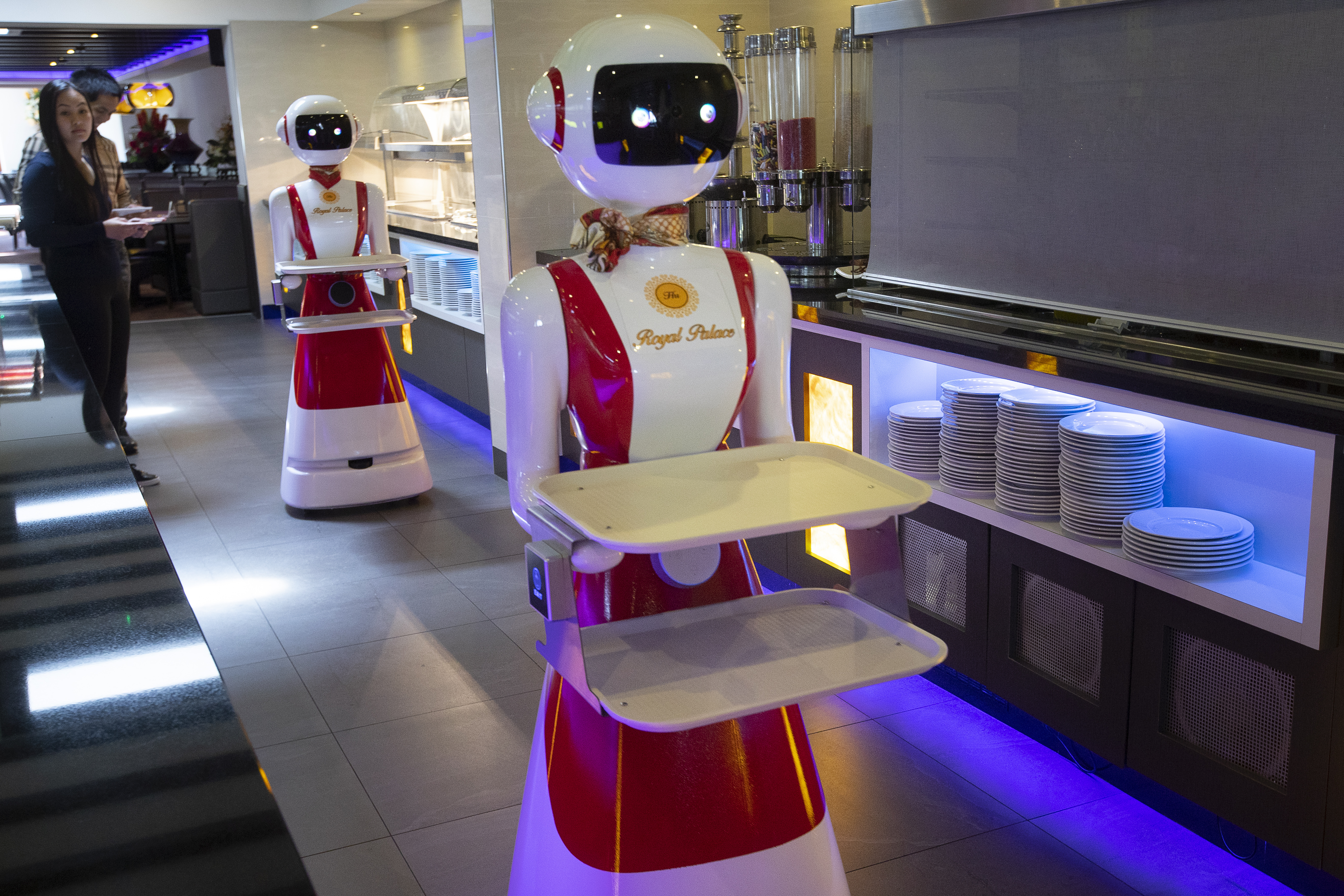 Leah Hu (left) and her brother Leon demonstrate the use of robots for serving purposes or for dirty dishes collection, as part of a tryout of measures to respect social distancing and help curb the spread of the COVID-19 coronavirus, at the family's Royal Palace restaurant in Renesse.