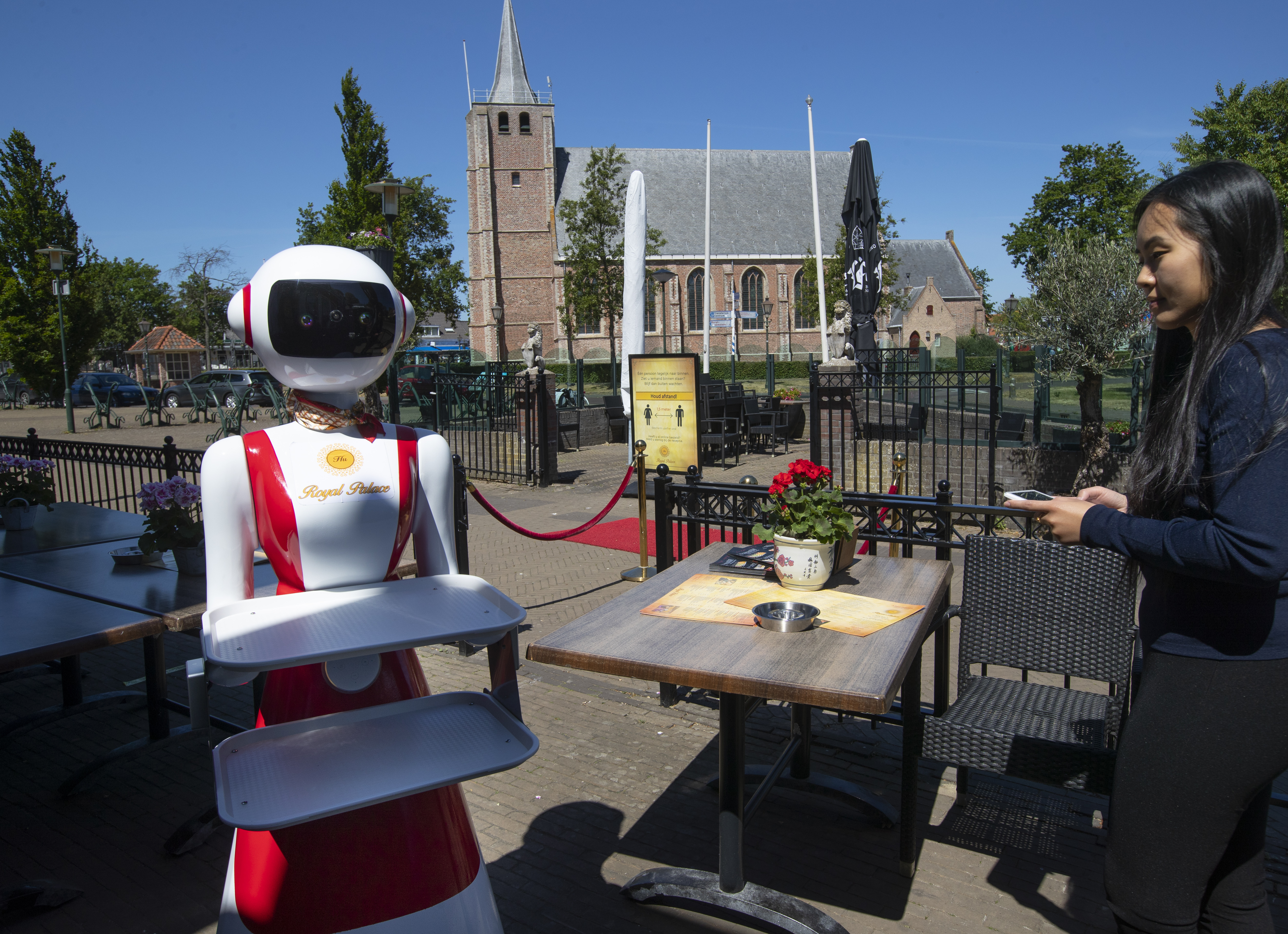 Leah Hu uses a tablet to demonstrate the use of a robot for serving purposes or for dirty dishes collection, as part of a tryout of measures to respect social distancing and help curb the spread of the COVID-19 coronavirus, at the family's Royal Palace restaurant in Renesse, on Wednesday.