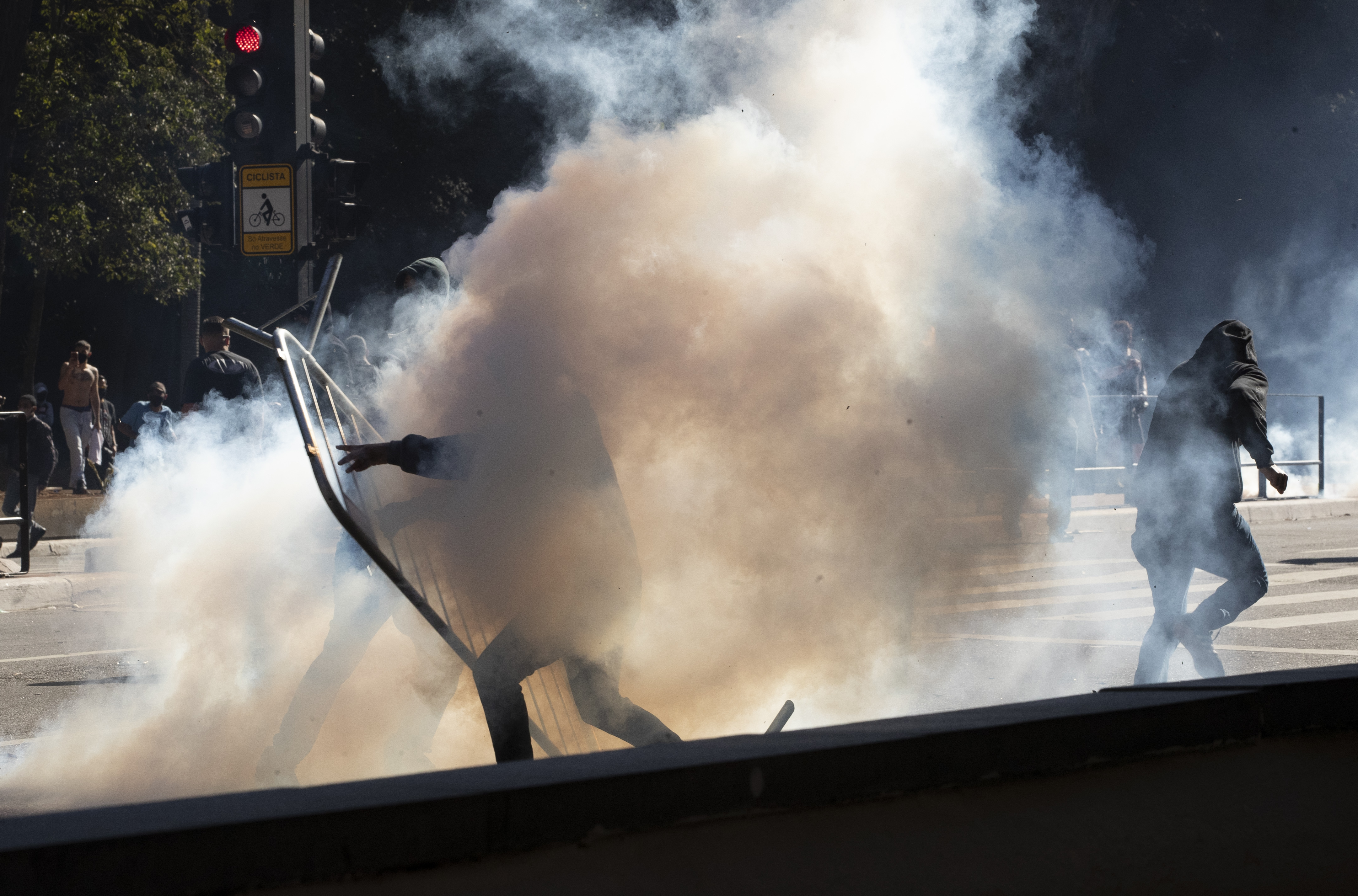 An anti-government demonstrator is engulfed by a cloud of teargas during clashes in Sao Paulo