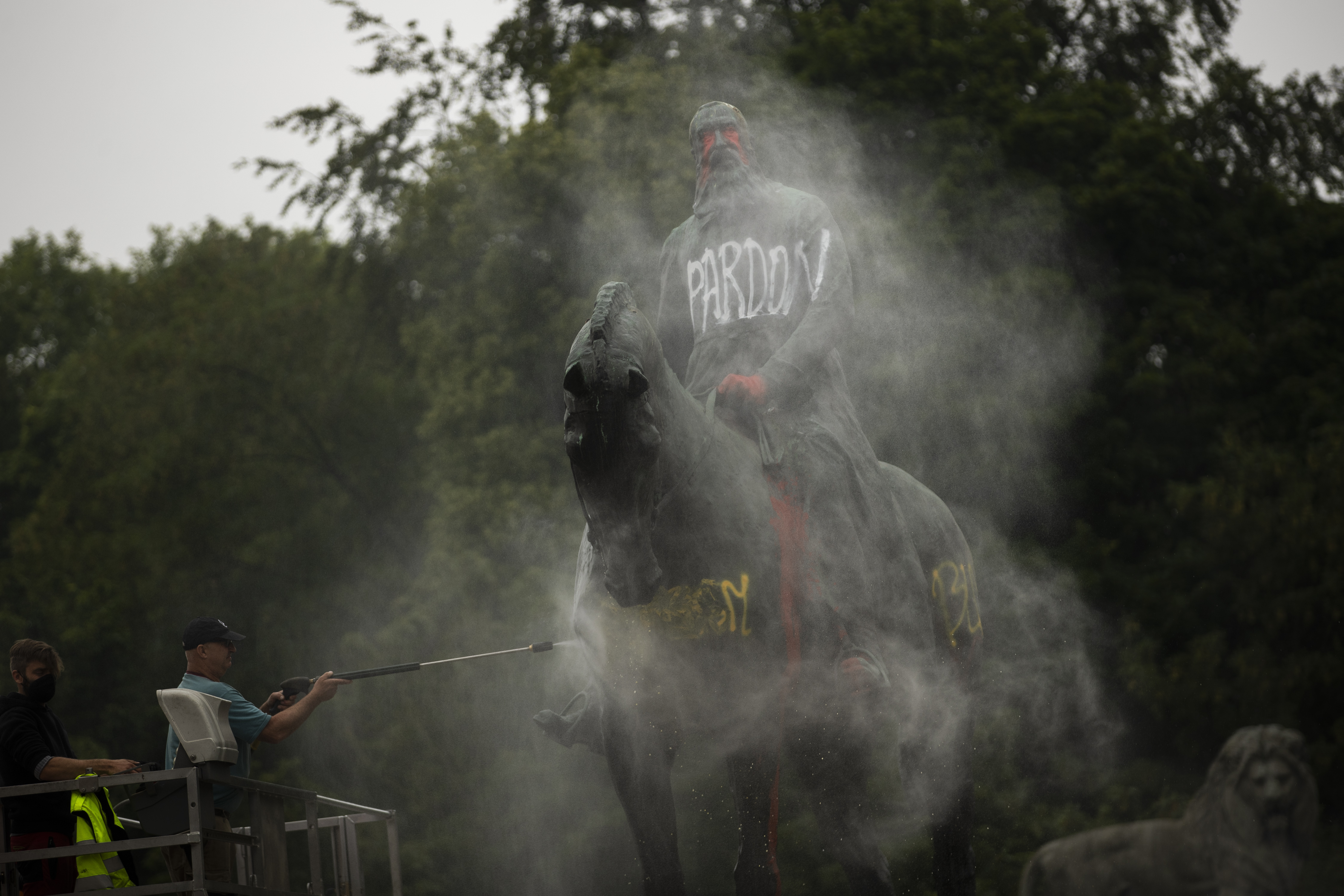 Workers clean graffiti from a statue of Belgium's King Leopold II in Brussels on Thursday.