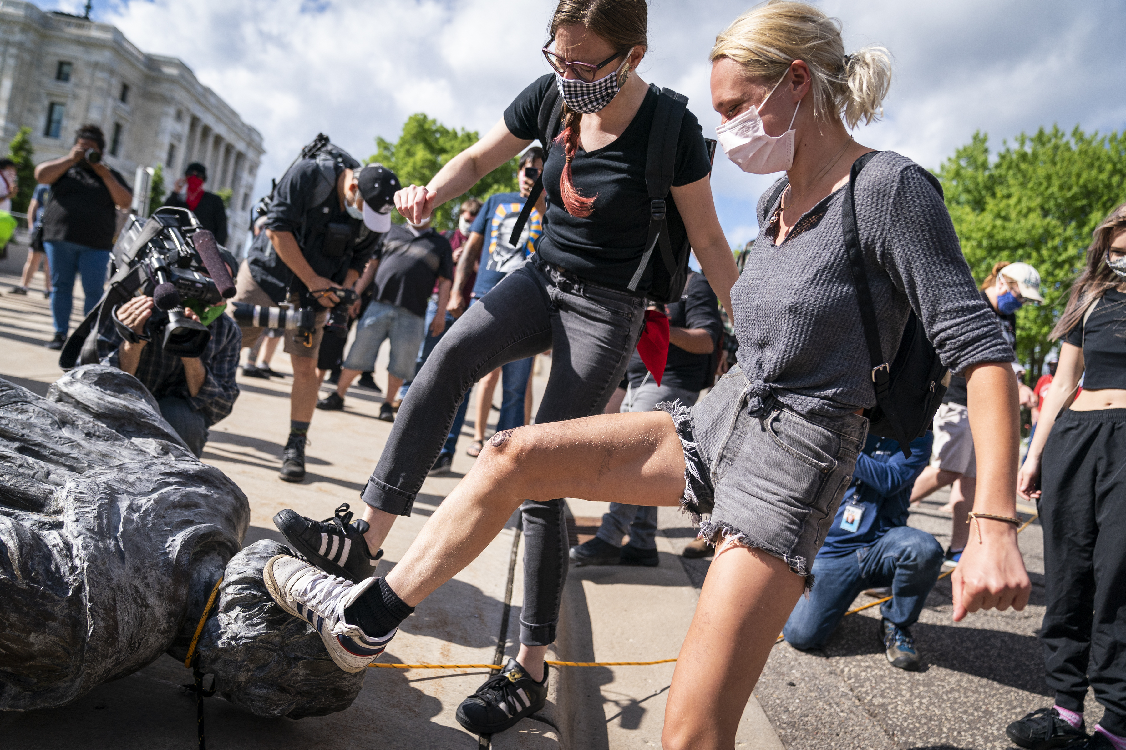 People take turns stomping the Christopher Columbus statue after it was toppled in front of the Minnesota State Capitol in St. Paul, Minn., on Wednesday.