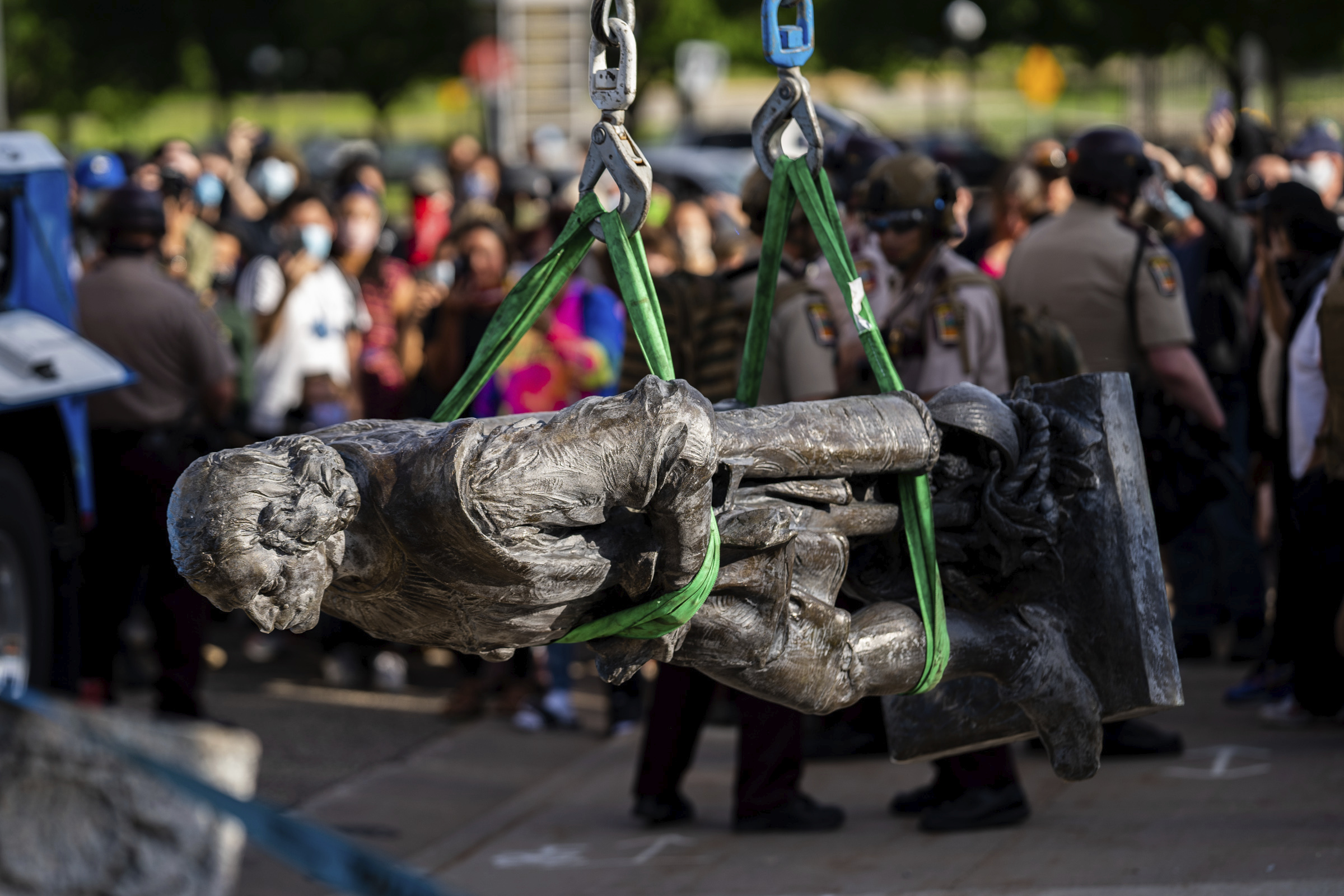 A statue of Christopher Columbus is lifted onto the back of a truck as people sing and celebrate at the Minnesota state Capitol in St. Paul, Minn., Wednesday.