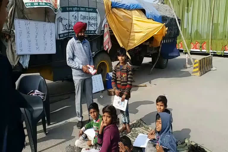 farmer teaching children of labourers on the road in sonipat