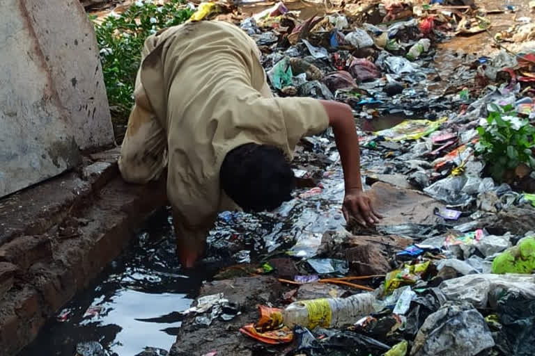 civil worker cleans cleans drainage in bare hands