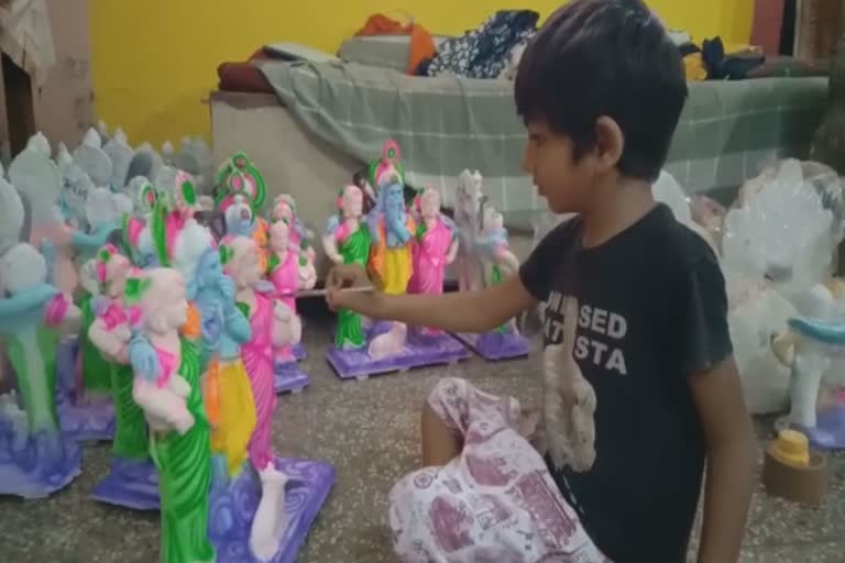 Child artist engaged in shaping Shri Krishna statue