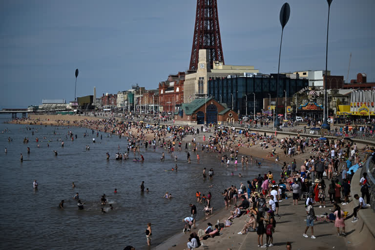 Beachgoers enjoy the sun and the sea at Blackpool, north west England on July 17, 2022. The UK's meteorological agency on Friday issued its first ever "red" warning for exceptional heat, forecasting record highs of 40 degrees Celsius next week. (Photo by Oli SCARFF / AFP)