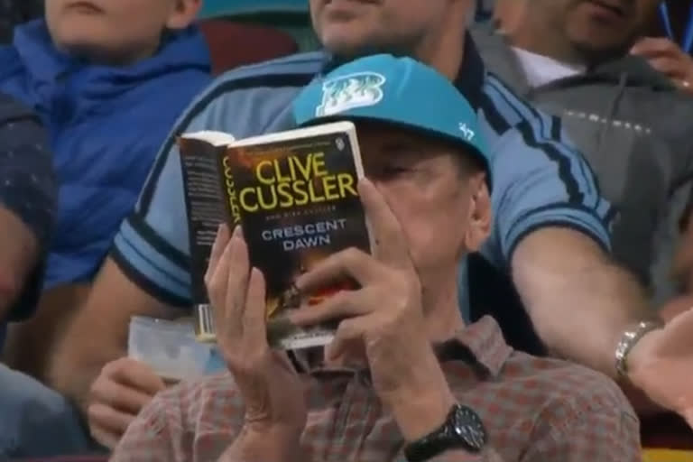 spectator reading book in gallery  england vs newzealand spectator reading book  england vs newzealand  t20 world cup 2022  ഐസിസി  കളിക്കിടിയിലെ പുസ്‌തകം വായന  ടി20 ലോകകപ്പ് സൂപ്പര്‍ 12  ടി20 ലോകകപ്പ്