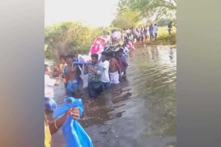 கழுத்தளவு நீரில் சடலத்தோடு கடக்கும் மக்கள்