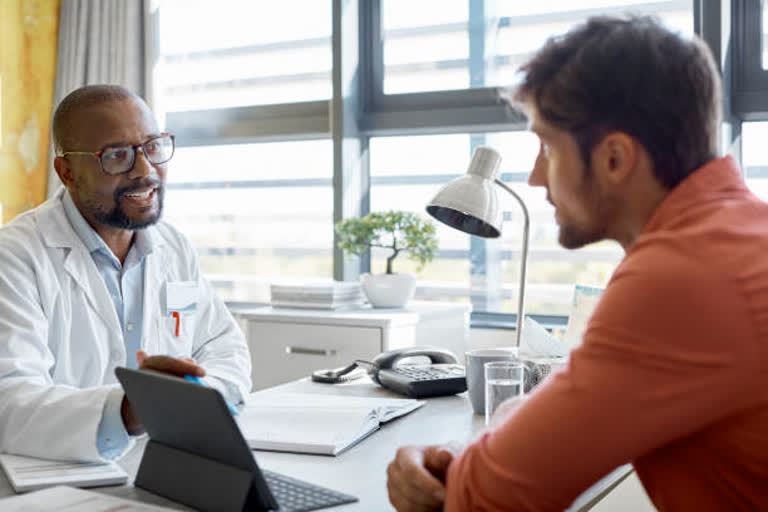 Male doctor discussing with patient in clinic