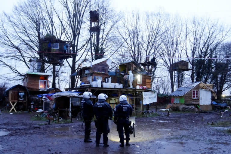 Police officers stand inside a camp of climate activists at the village Luetzerath, near Erkelenz, Germany, Thursday, Jan. 12, 2023. Police have entered the condemned village in to evict the climate activists holed up at the site in an effort to prevent its demolition, to make way for the expansion of a coal mine. (AP Photo/Michael Probst)