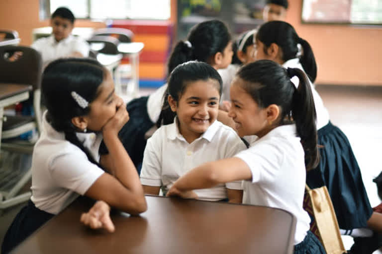 Girl children gossiping in classroom