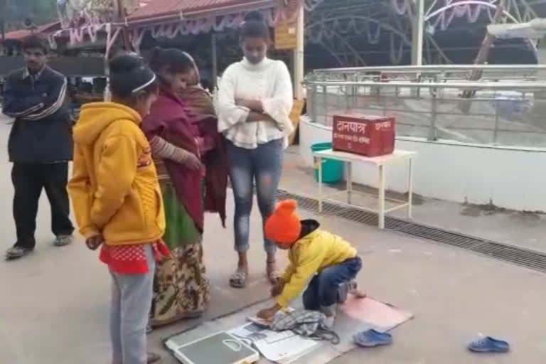 Eight year old boy sits with a measuring machine at the Triveni Ghat in the Rashishish city