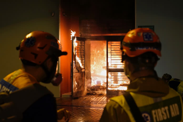 First aid volunteers try to extinguish a fire set by local residents at a building of the Fai Ming Estate, in Fanling district of Hong Kong, Sunday