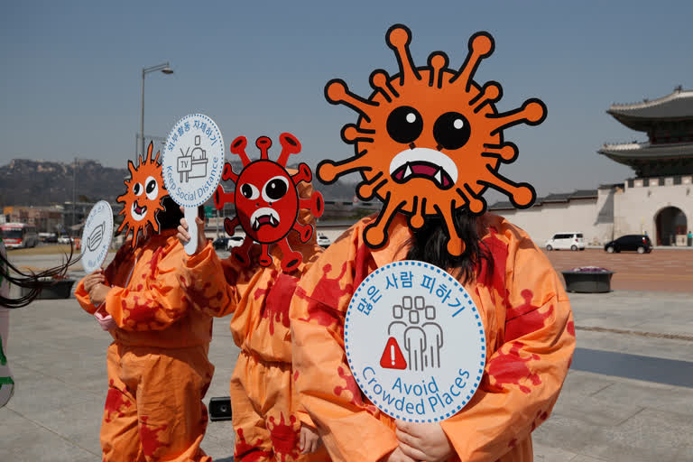 Environmental activists wearing masks symbolizing a virus hold signs during a new coronavirus prevention campaign in Seoul