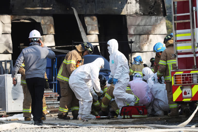 Firefighters prepare to carry an injured worker after a fire engulfed a construction site in Icheon, South Korea