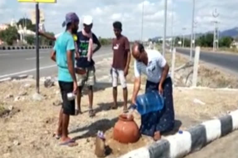 a person from guntur keeping water for migrants in national highway