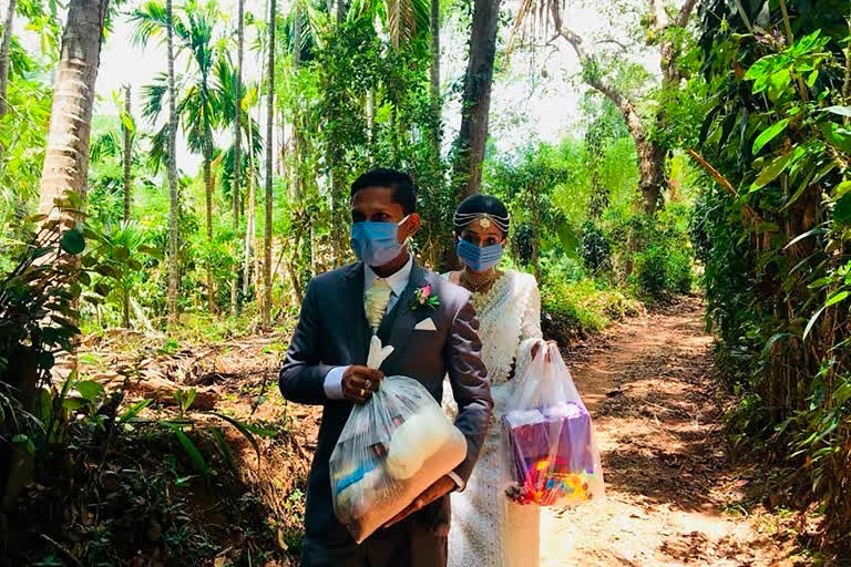 Darshana Kumara Wijenarayana and his bride Pawani Rasanga walk with packets of food to distribute in the small town of Malimbada, about 160 kilometers south of the capital Colombo.