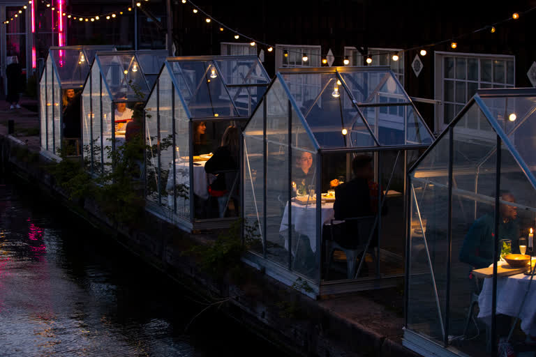 Staff at the Mediamatic restaurant serve food to volunteers seated in small glasshouses during a try-out of a setup which respects social distancing abiding by government directives to combat the spread of the COVID-19 coronavirus in Amsterdam.