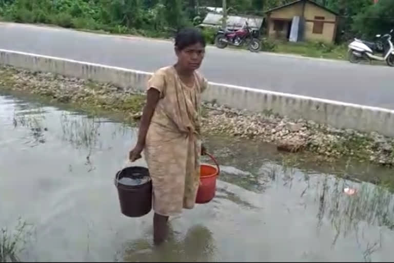 In Golaghat a woman  drinks water from a road for makes a live