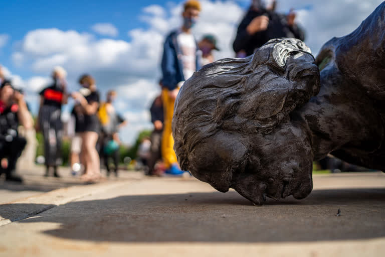 People stand around the fallen Christopher Columbus statue at the Minnesota state Capitol in St. Paul, Minn., on Wednesday.