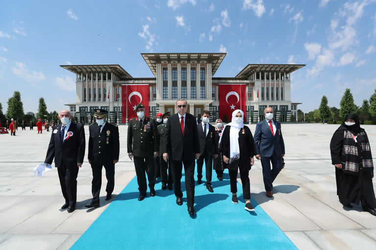 Turkey's President Recep Tayyip Erdogan and family members of coup victims walk to place a bouquet of flowers at the "Martyrs Monument" outside his presidential palace, in Ankara, on Wednesday.