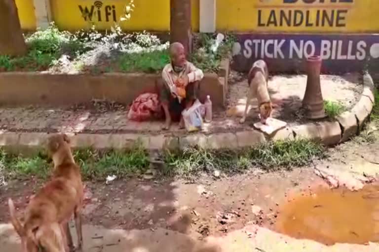 A beggar who is feeding a dog