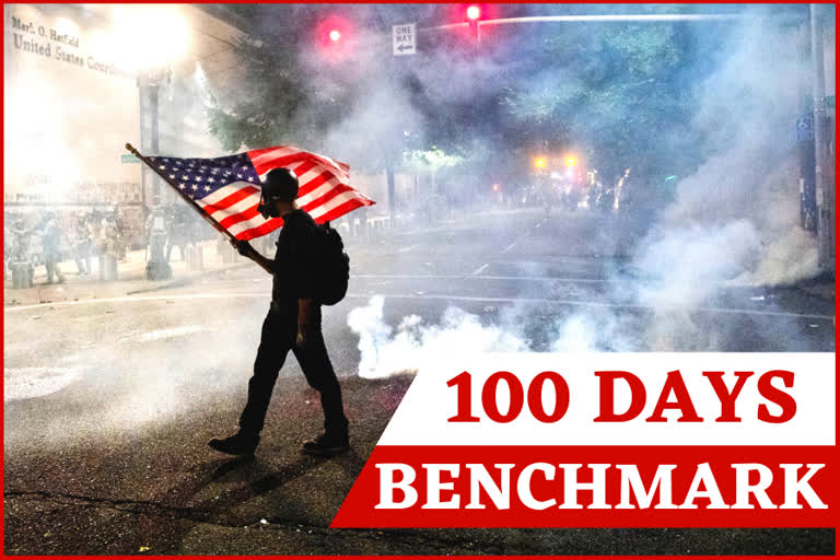 In this July 21, 2020, file photo, a Black Lives Matter protester carries an American flag as teargas fills the air outside the Mark O. Hatfield United States Courthouse in Portland, Ore.