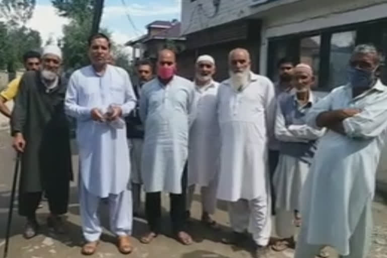 Locals protest against the government on a dilapidated road in Sopore