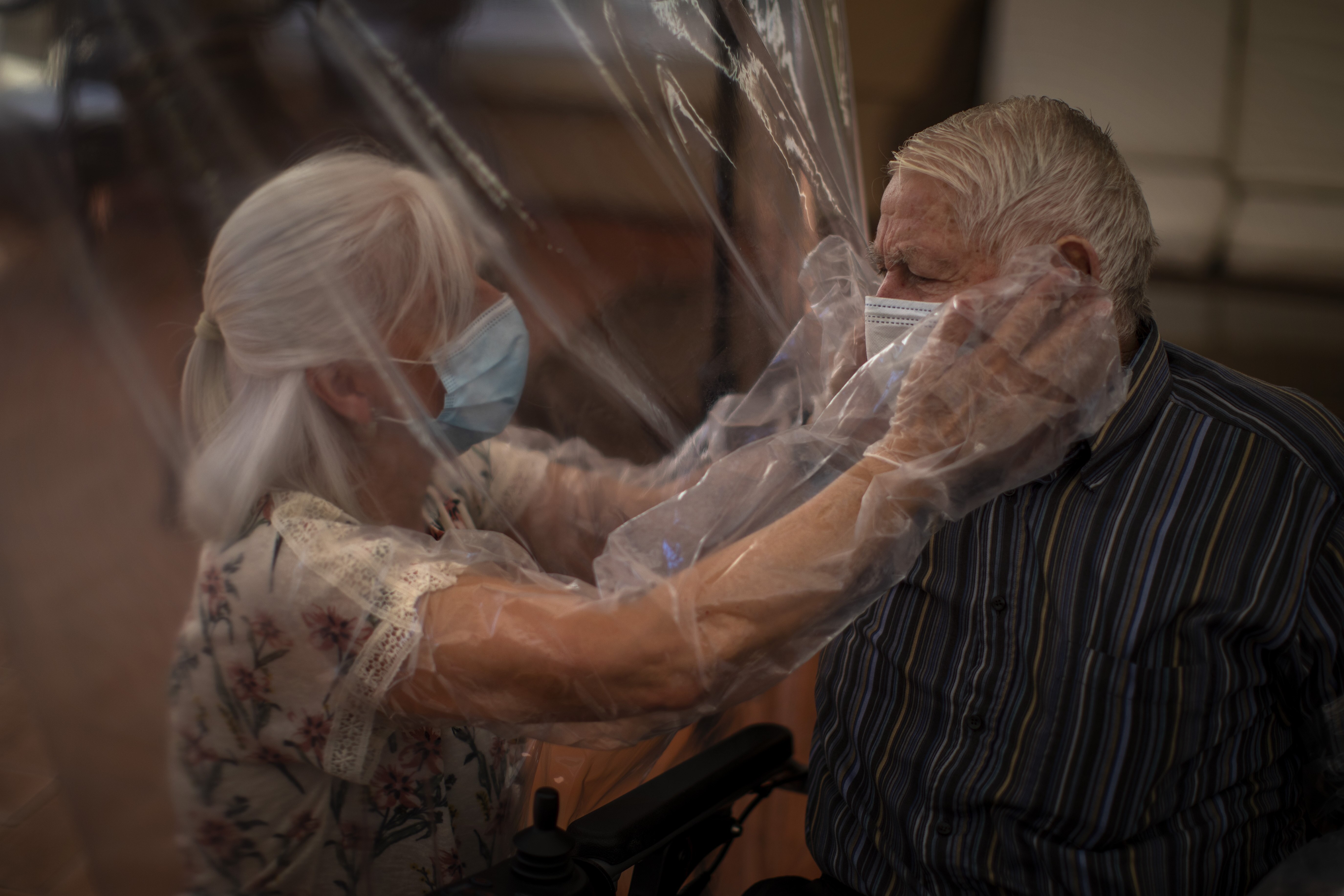 Dolores Reyes Fernández touches the face of her father José Reyes Lozano for the first time in nearly four months as visits resume to a nursing home in Barcelona, Spain.