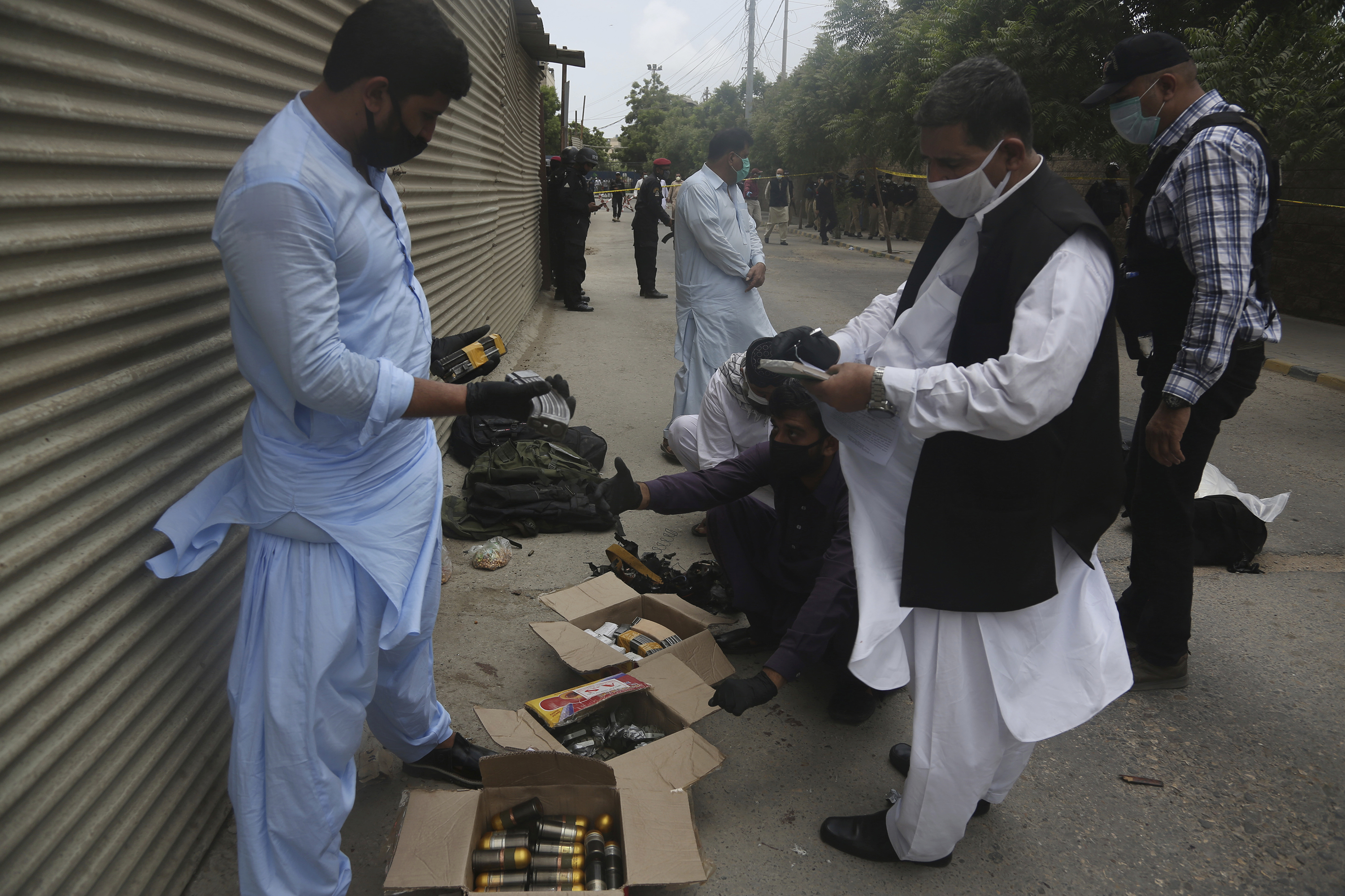 Security personnel examine confiscated ammunition from attackers outside the Stock Exchange Building in Karachi, Pakistan on Monday