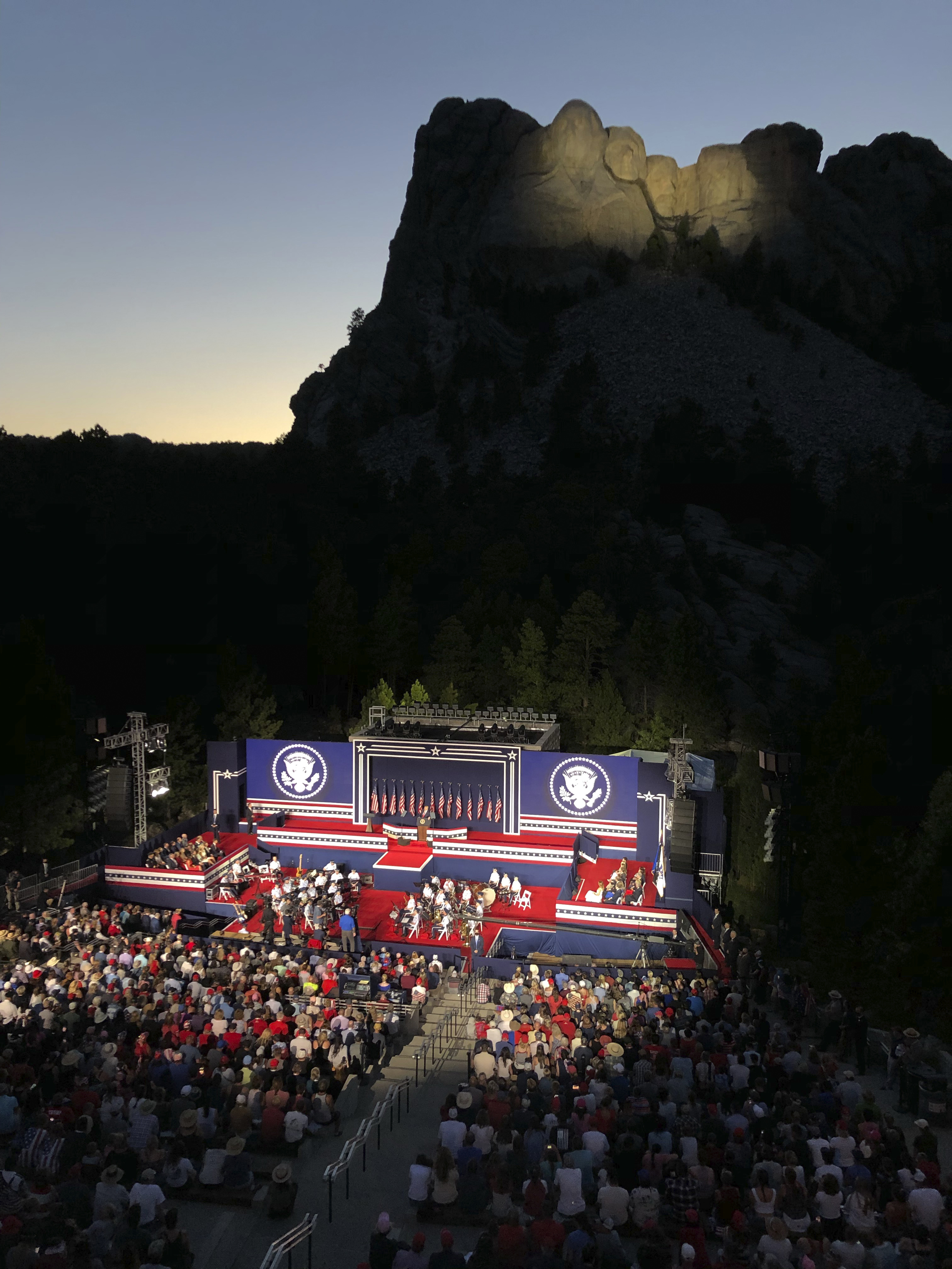 President Donald Trump, accompanied by first lady Melania Trump, stands during the national anthem with a flyover by the U.S. Navy Blue Angles at Mount Rushmore National Memorial, on Friday.