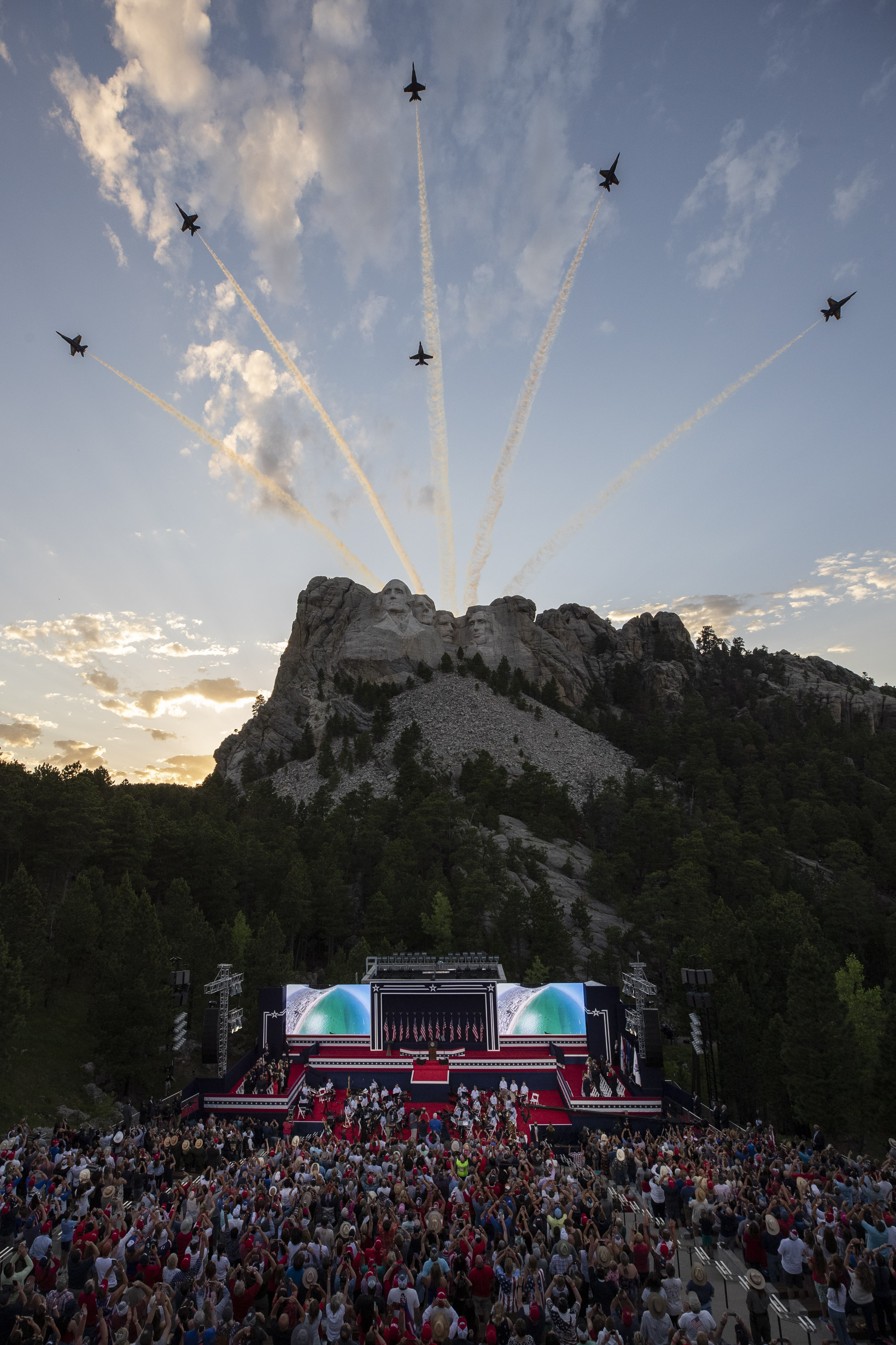 President Donald Trump, accompanied by first lady Melania Trump, stands during the national anthem with a flyover by the U.S. Navy Blue Angles at Mount Rushmore National Memorial, on Friday.