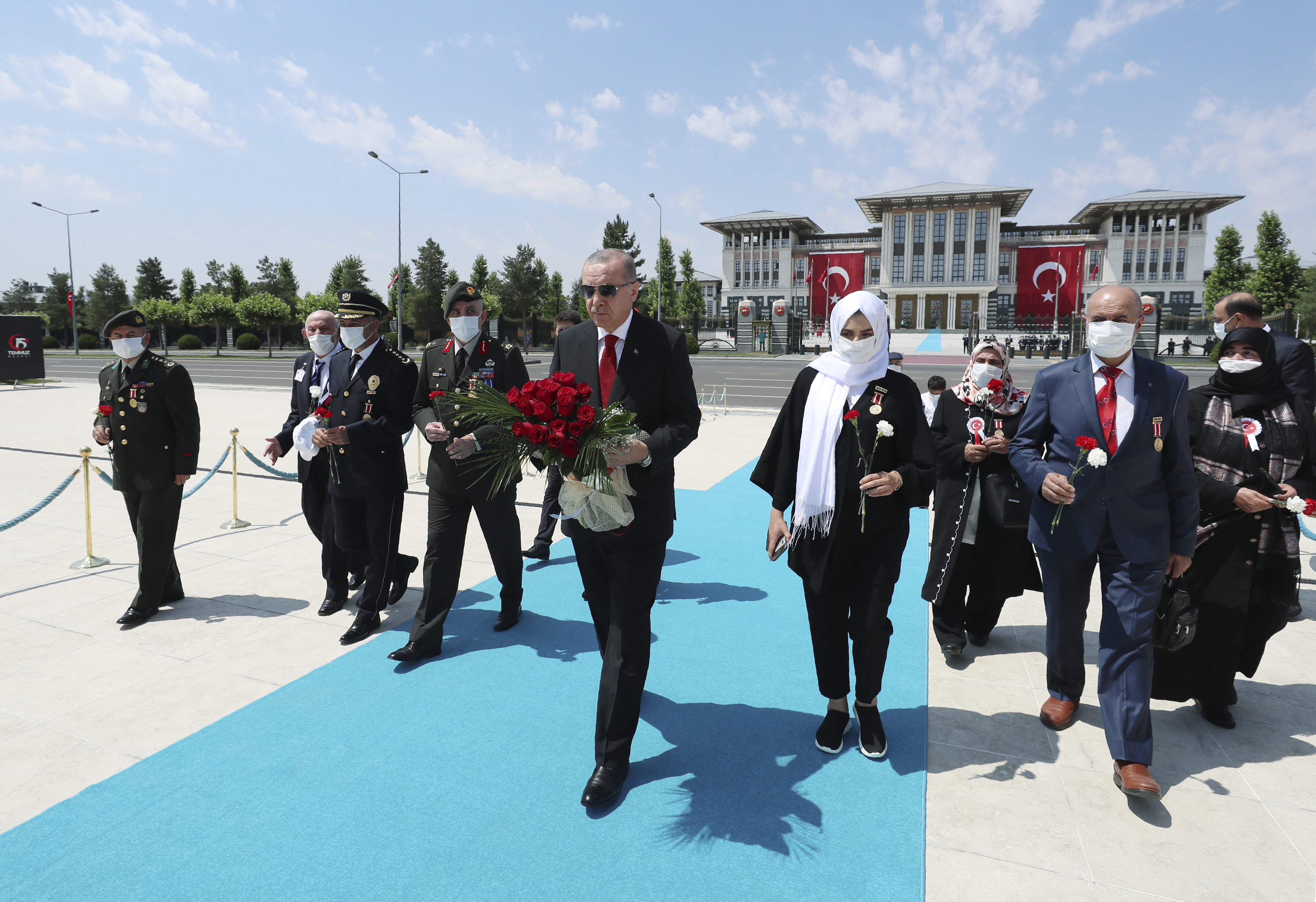 Turkey's President Recep Tayyip Erdogan and family members of coup victims walk to place a bouquet of flowers at the 