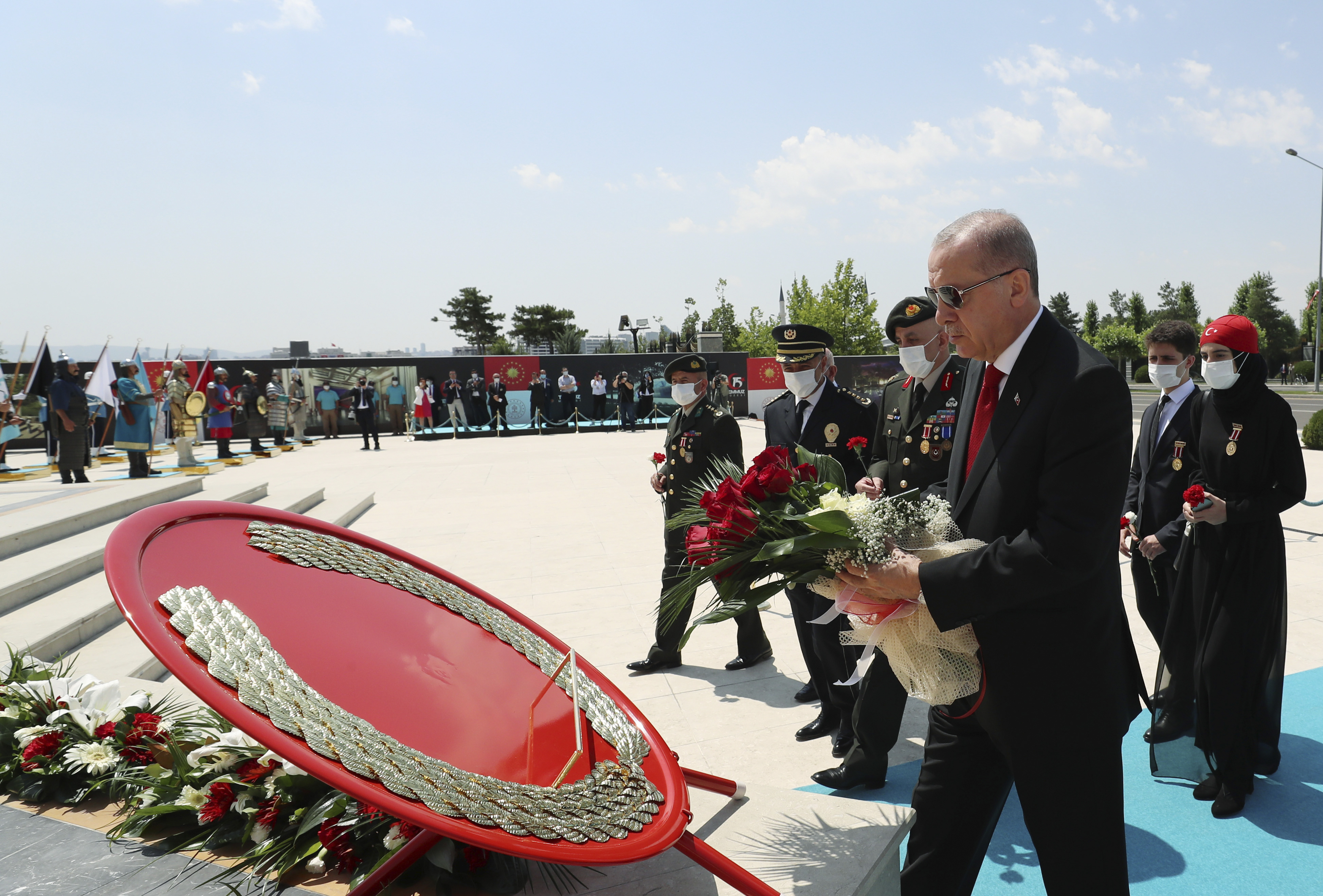 Turkey's President Recep Tayyip Erdogan and family members of coup victims walk to place a bouquet of flowers at the 