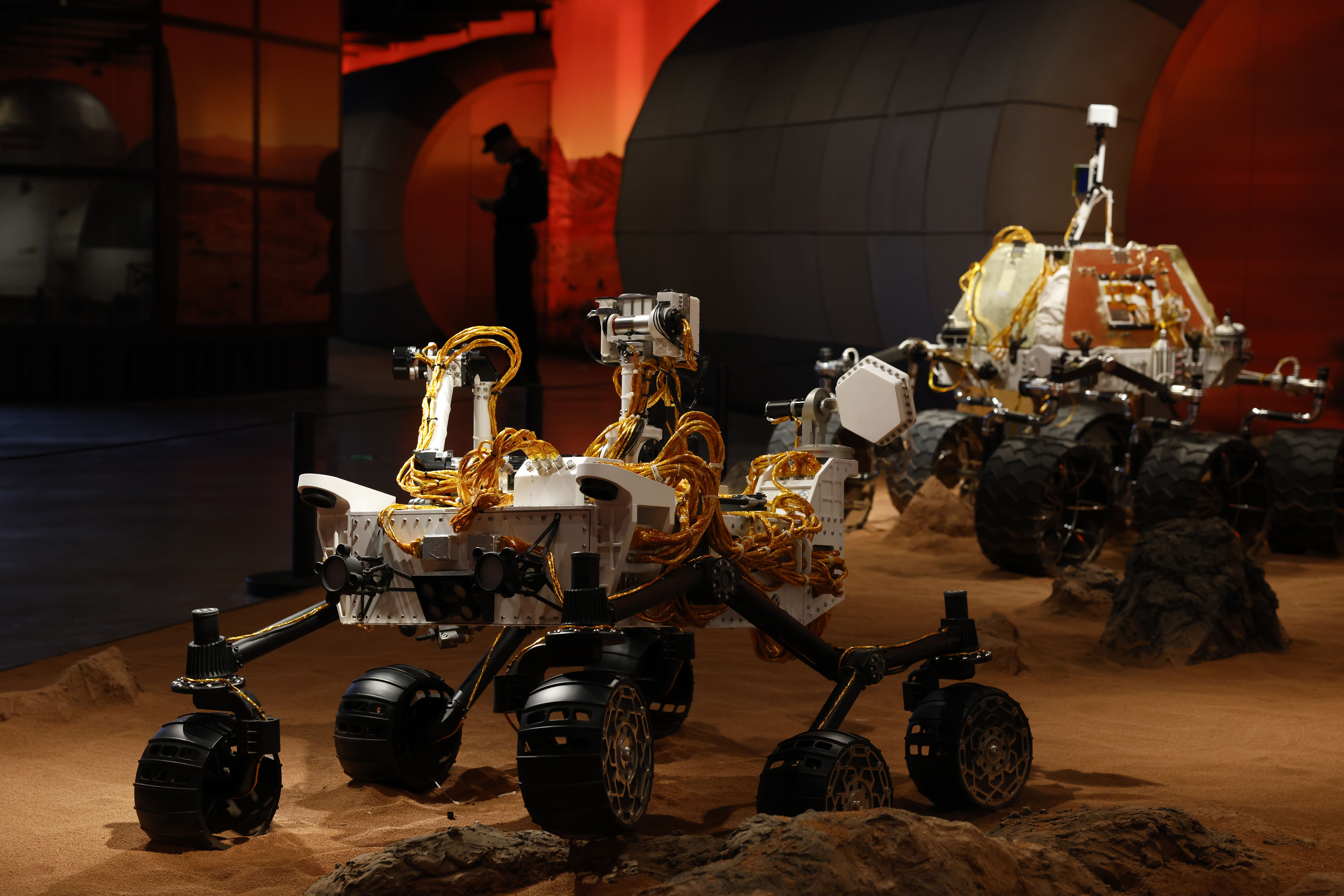 A security guard is silhouetted near a display depicting rovers on Mars during an exhibition in Beijing on Thursday.