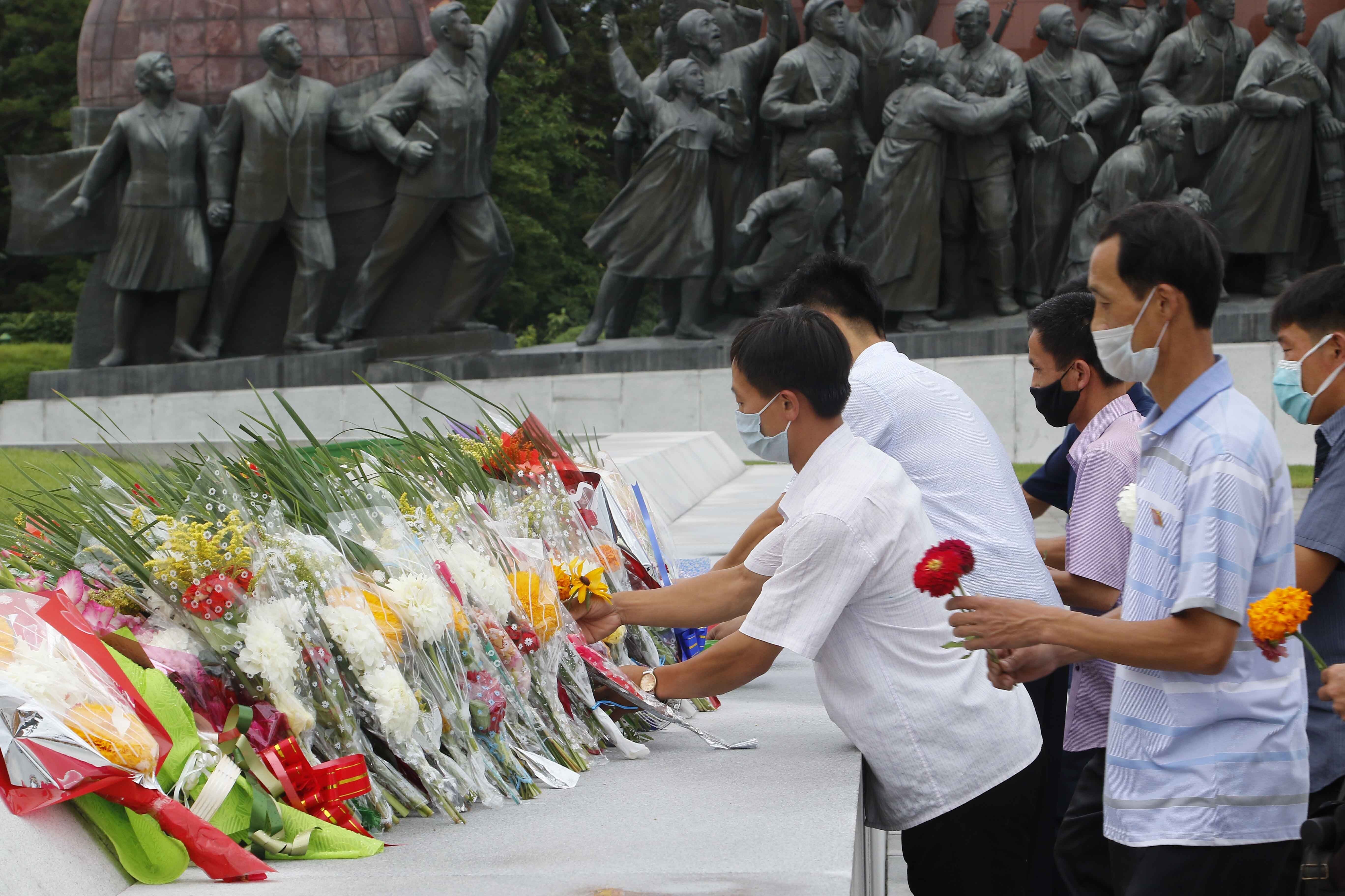 People lay flowers the statues of former North Korean leaders Kim Il Sung and Kim Jong Il on the occasion of the 67th anniversary of the end of the Korean War, which the country celebrates as the day of 