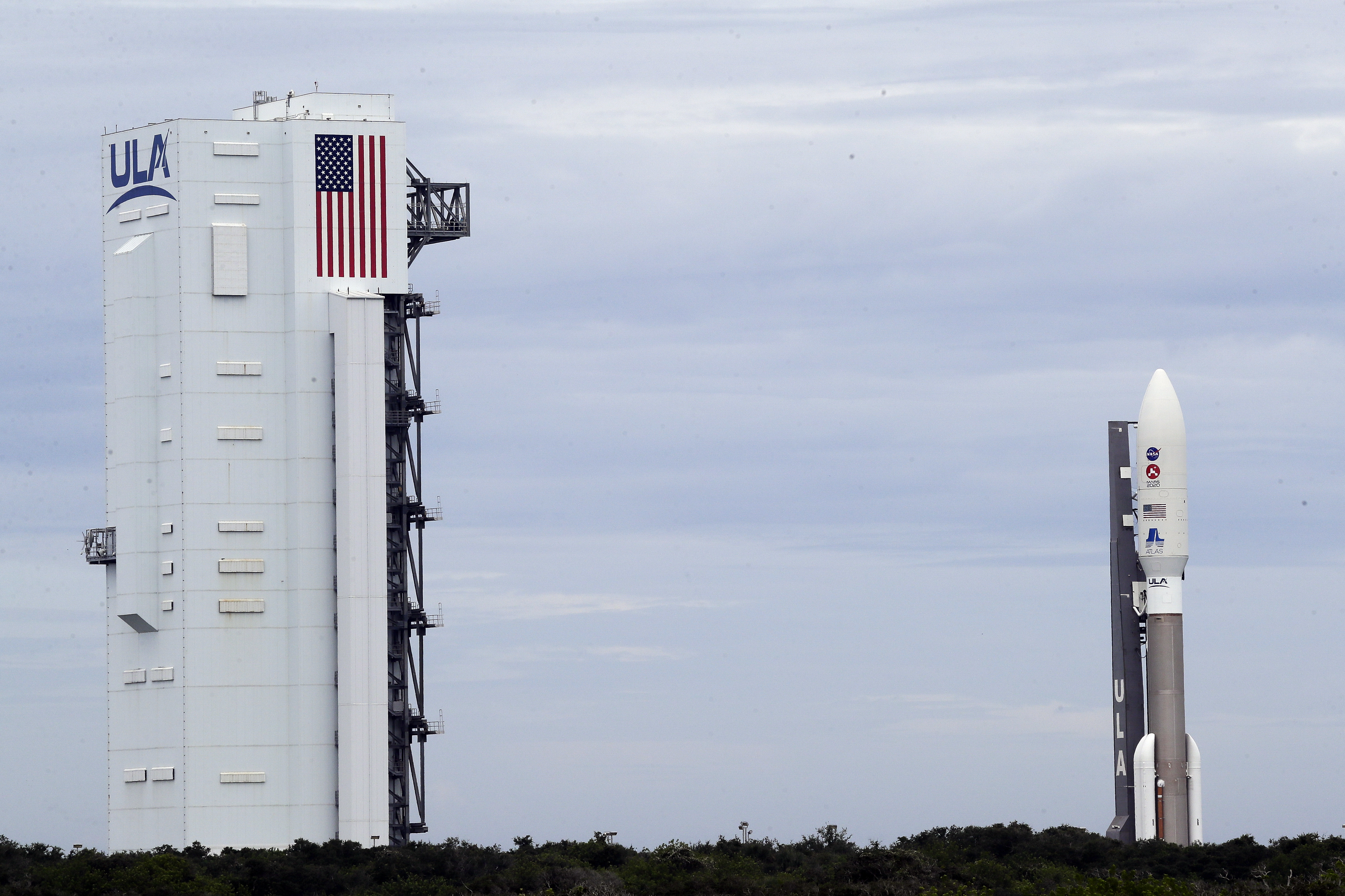 A United Launch Alliance Atlas V rocket that will launch to Mars leaves the vertical integration facility, left, as it rolls out to Space Launch Complex 41 at the Cape Canaveral Air Force Station on Tuesday in Cape Canaveral.