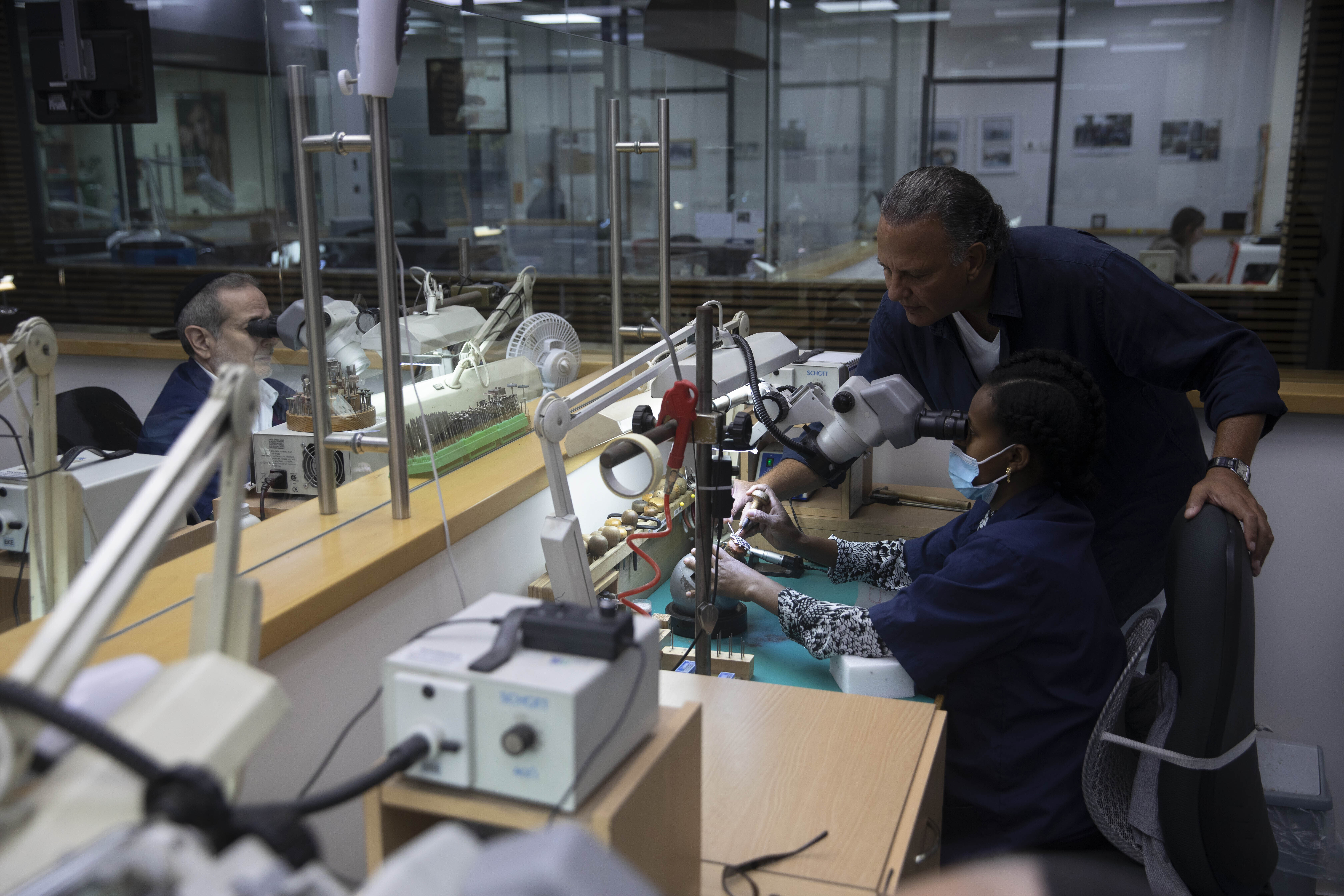 Isaac Levy, owner of Israeli jewelry company Yvel looks at a worker and parts of a mask in Motza near Jerusalem, on Sunday.