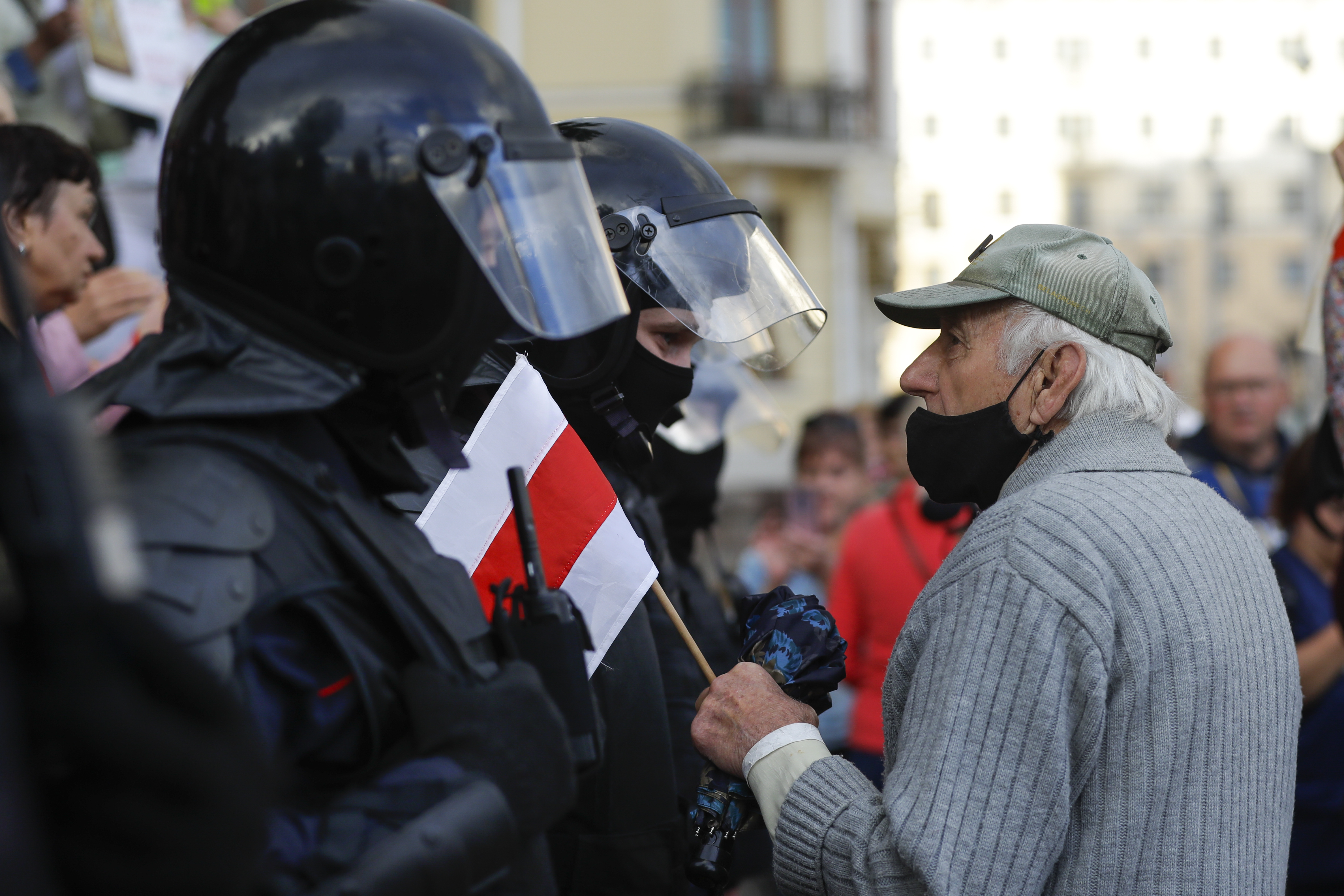 An elderly protester speaks to a policeman holding an old Belarusian national flag in front of riot police blocked Independence Square in Minsk, Belarus, Thursday.