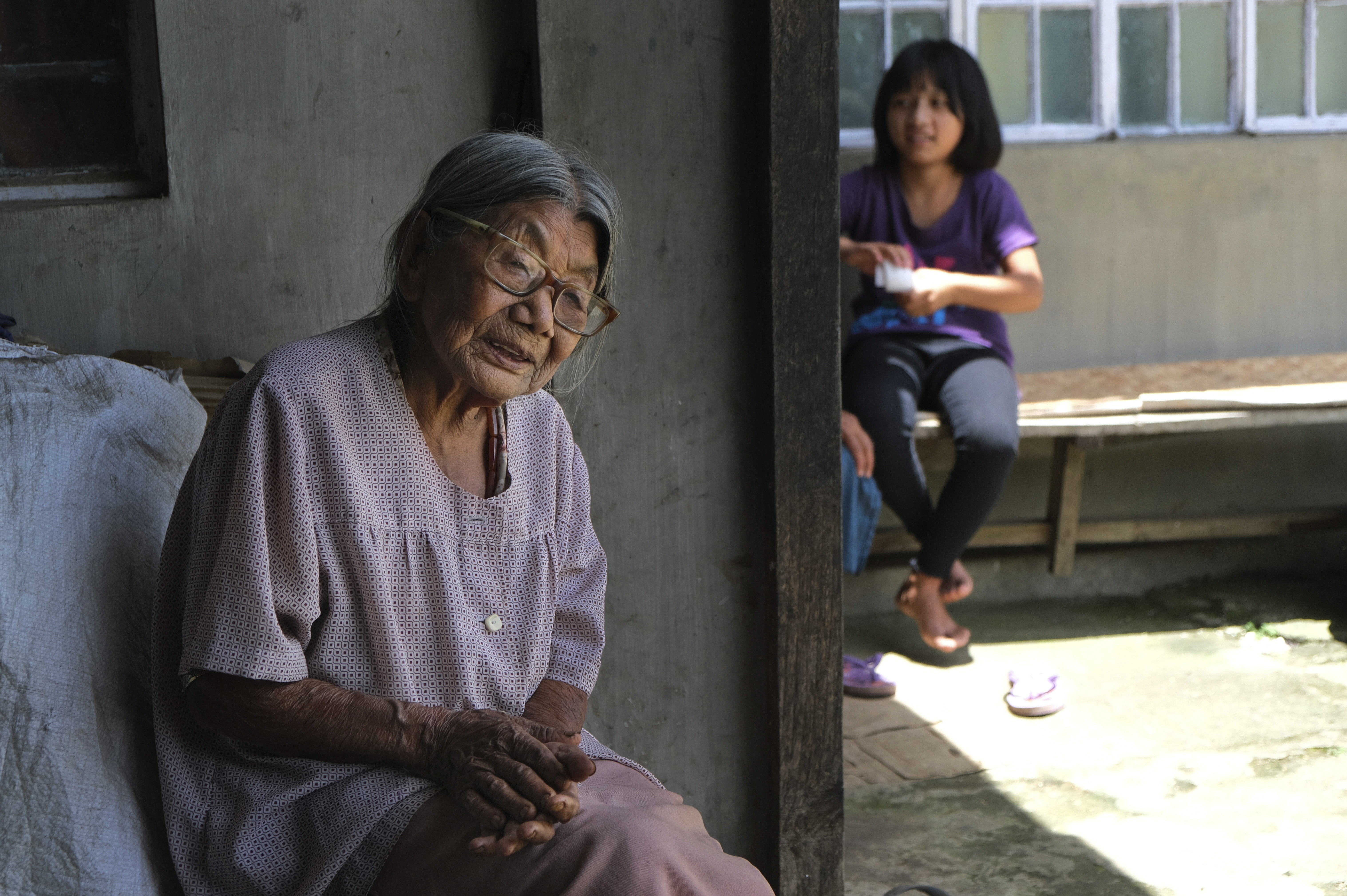 Kuozeu Vizo, a 98-year-old Angami Naga woman, recounts her memory of the bloody battle between the Japanese and British Commonwealth forces that took place in her village during the Second World War, as her granddaughter sits by the side outside their home in Kohima. (File)