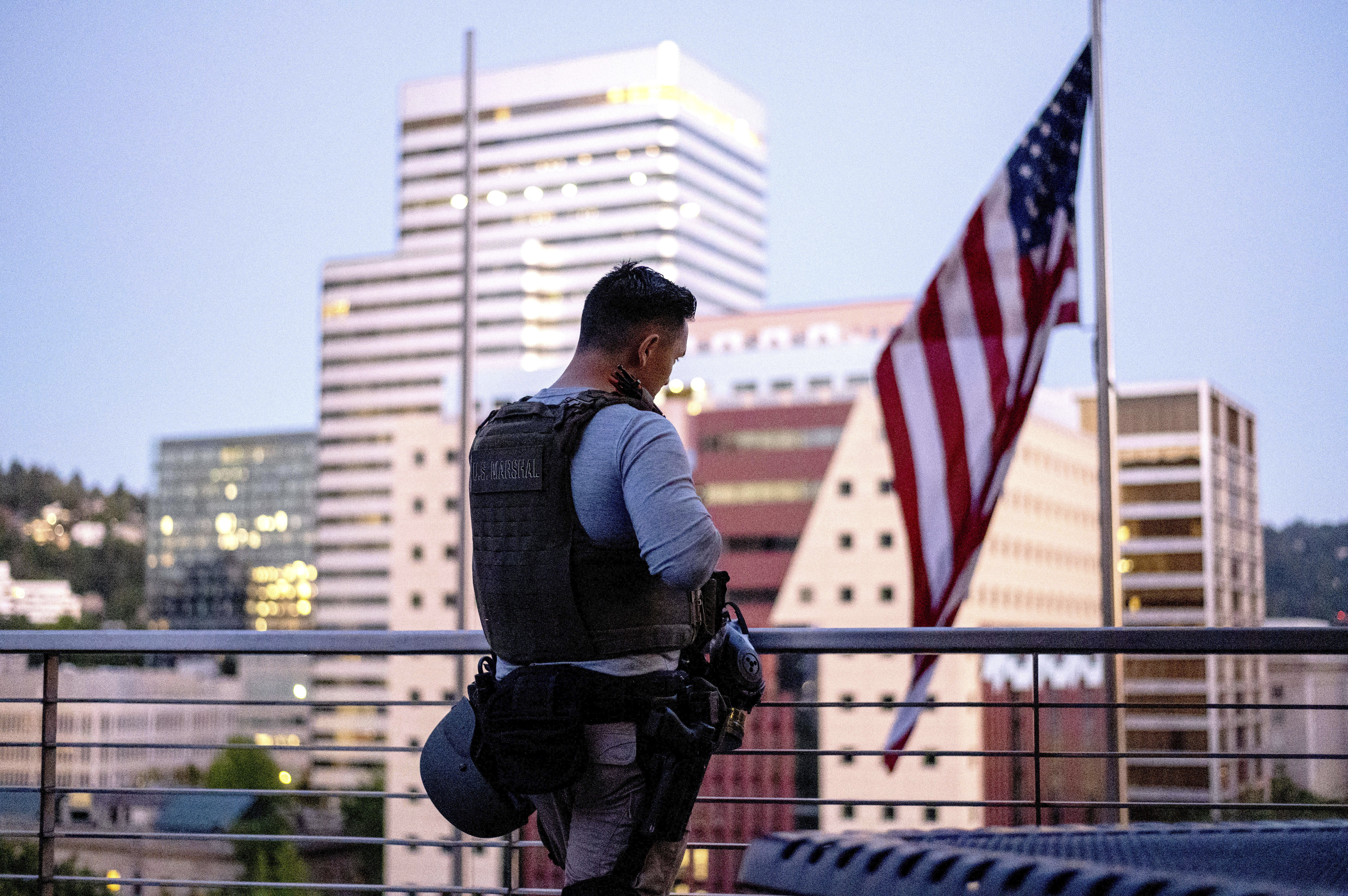 In this July 26, 2020, file photo, after a night of facing off against protesters, a deputy U.S. marshal takes a break on a rooftop terrace at the Mark O. Hatfield U.S. Courthouse in Portland, Ore.
