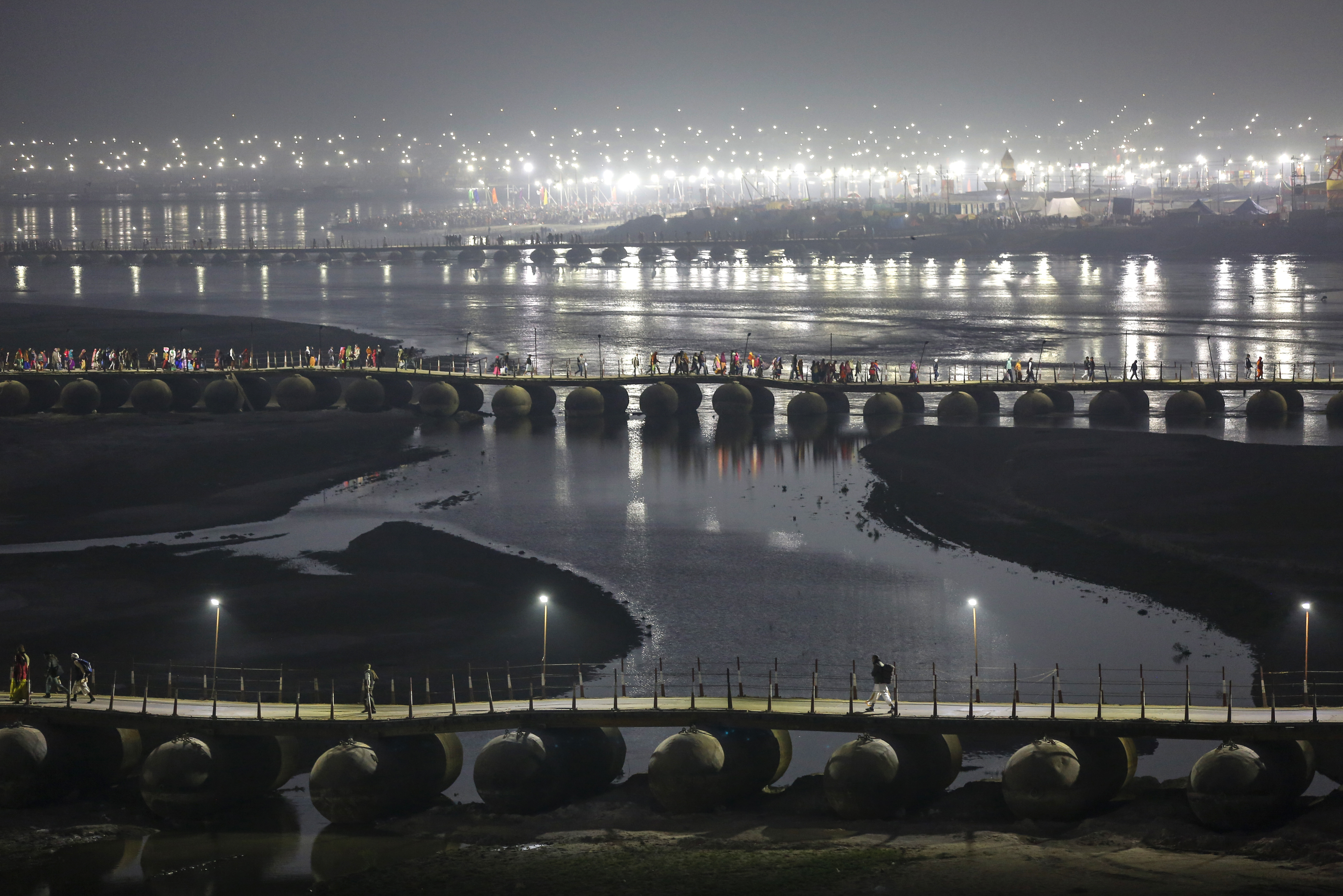 Pilgrims walk on a pontoon bridge before dawn at Sangam, the confluence of rivers Ganges, Yamuna, and mythical Saraswati during Magh Mela, a festival that attracts millions of pilgrims every year, in Prayagraj in Uttar Pradesh.